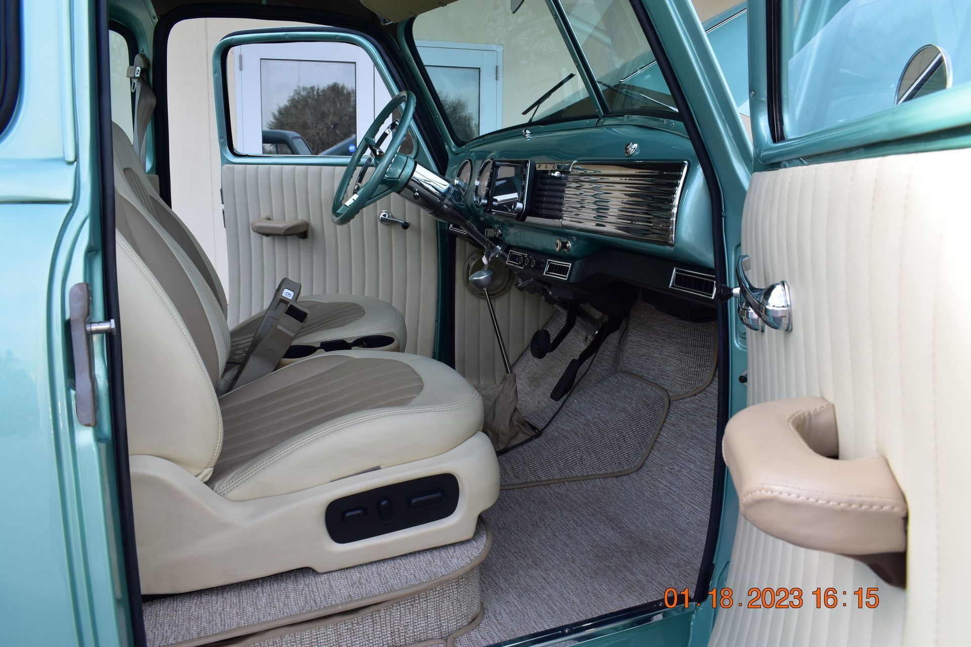 Open car door showing beige vinyl interior with turquoise dashboard and steering wheel