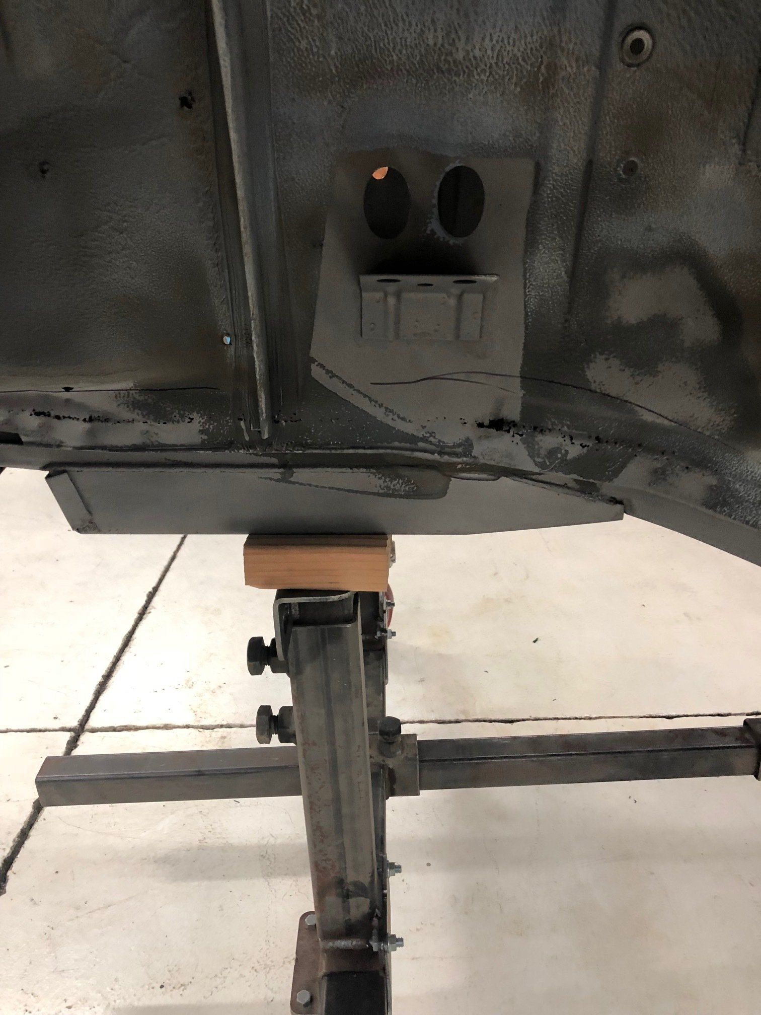 Underside of a car raised on a lift in a garage, showing the rear exhaust area.