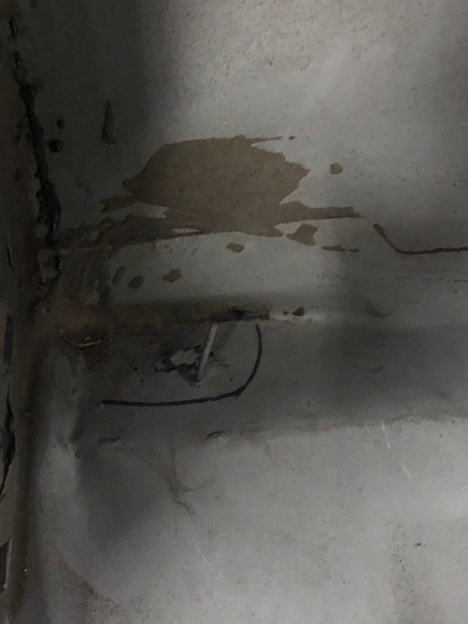 Damaged ceiling corner with water stains, peeling paint, and a small exposed fixture or wire
