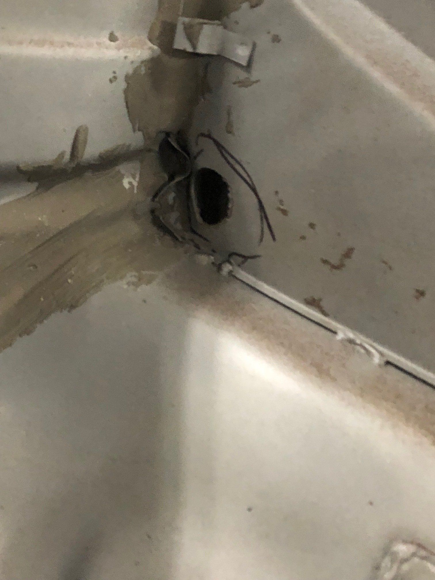 Damaged corner wall with a large hole and exposed wires above a sink