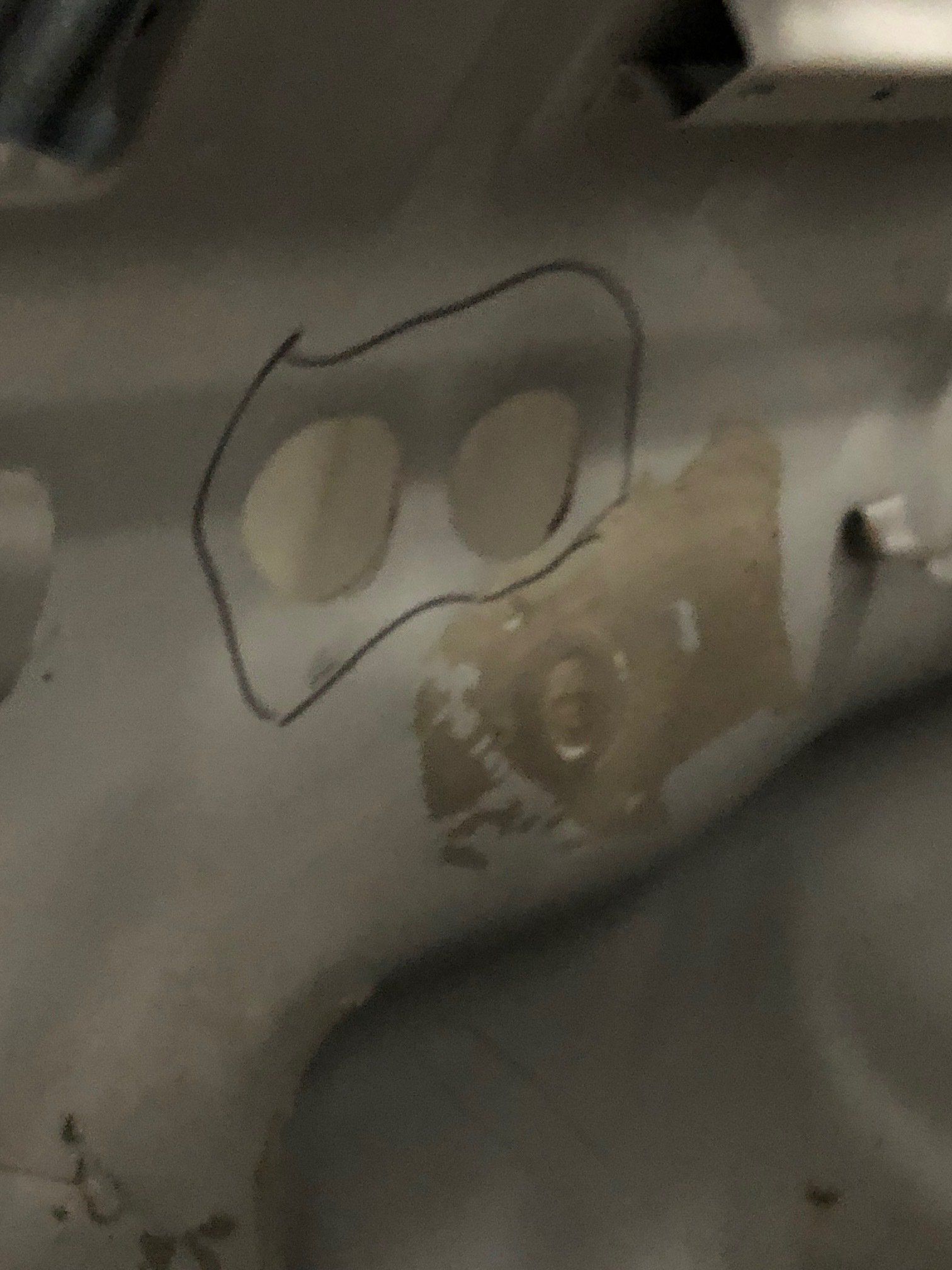 Close-up of a gray metal surface with two white oval cutouts outlined in black.