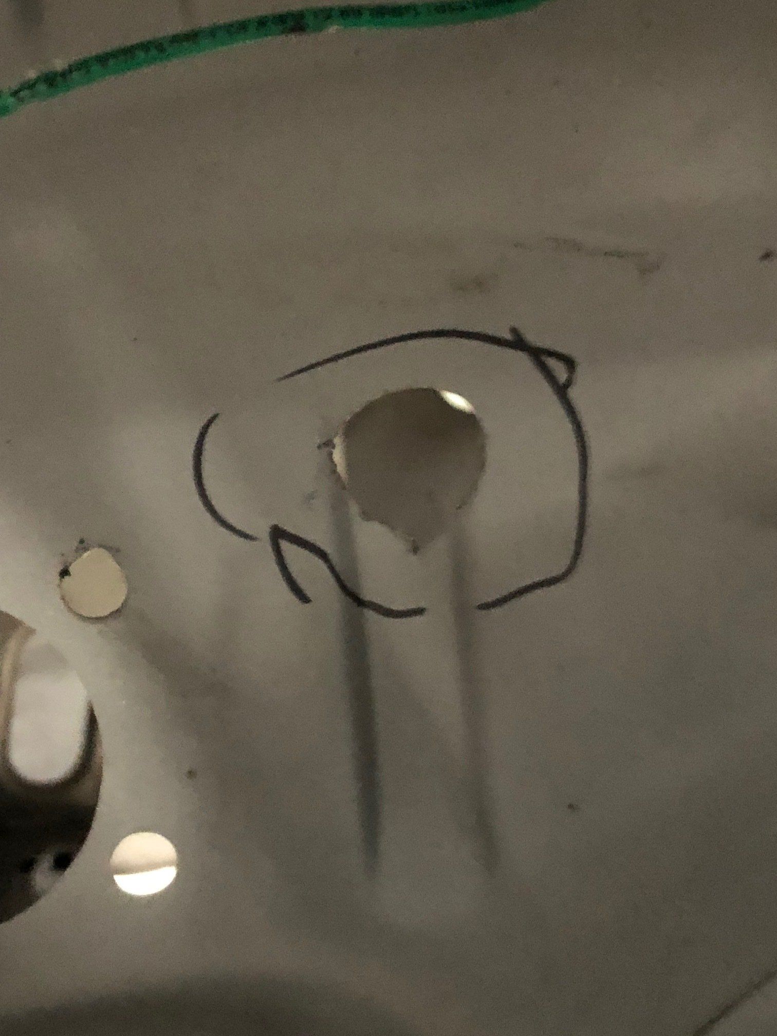 Close-up of a gray fabric with a torn hole outlined in black marker.