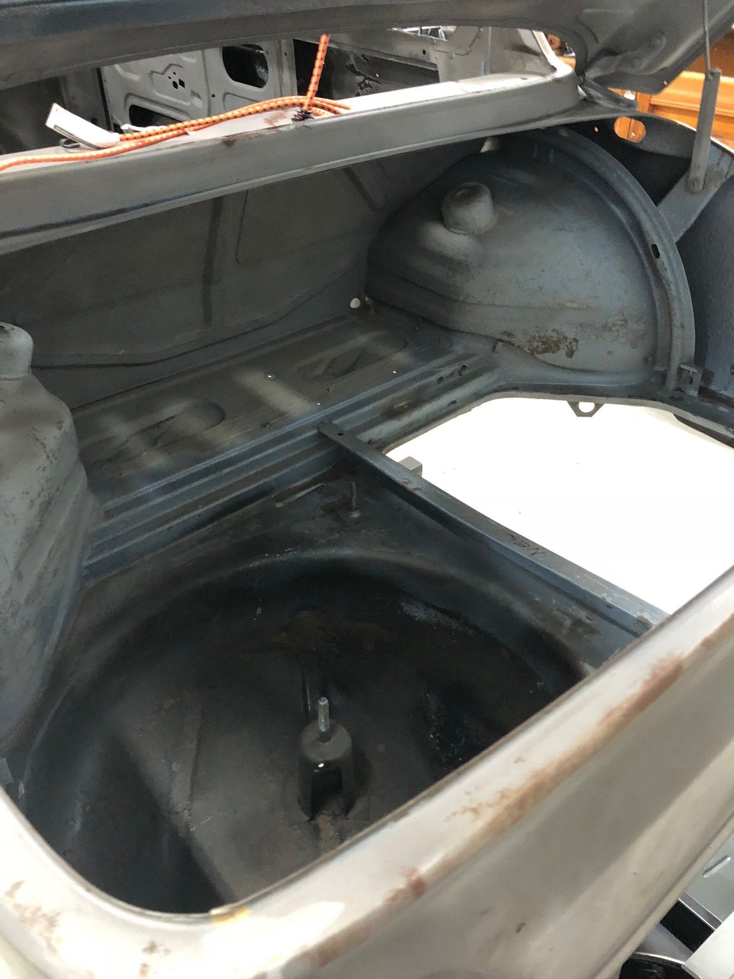 Open car trunk with a spare tire well and exposed interior metal panels.