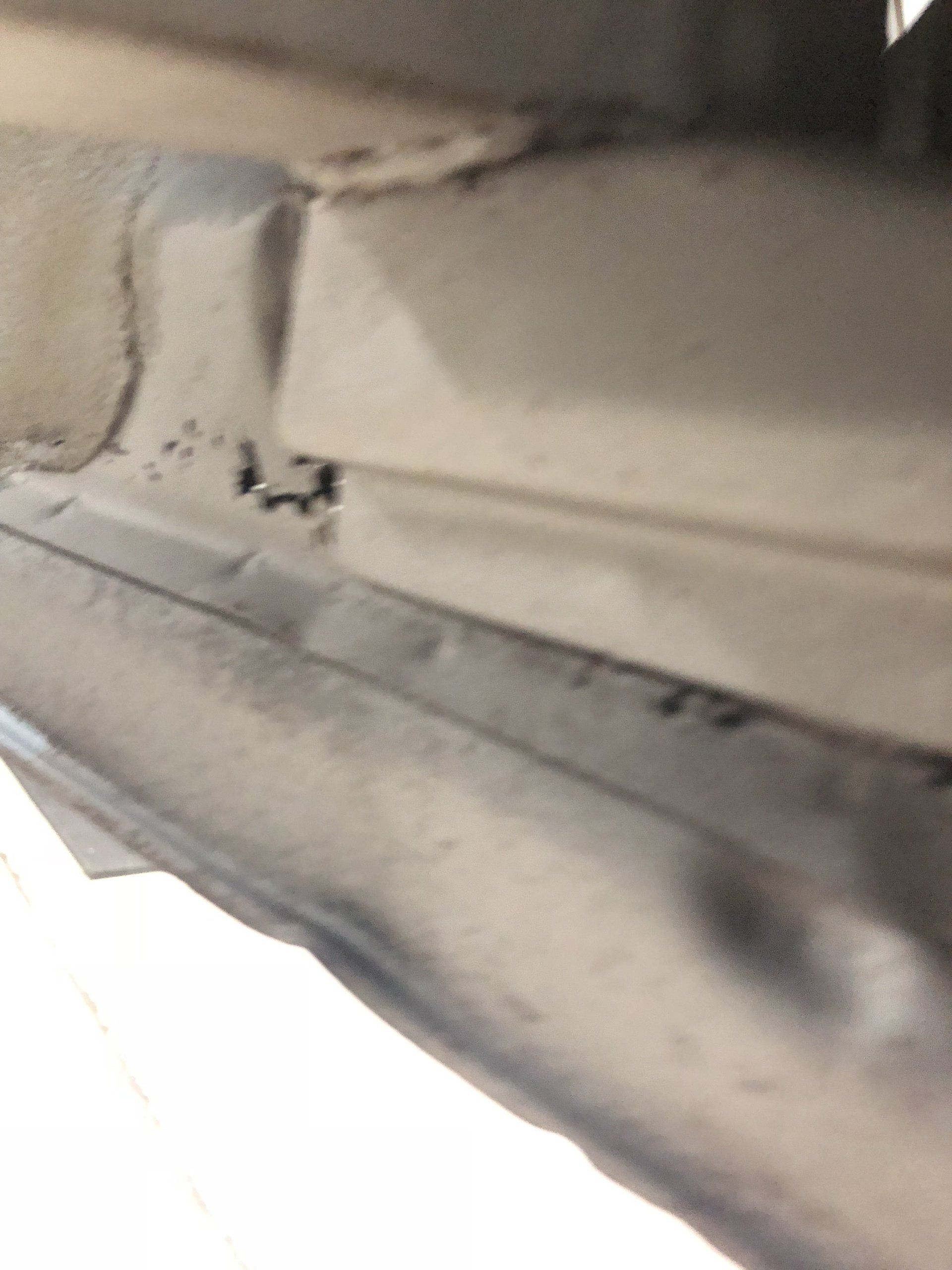 Close-up of a dusty white vehicle interior panel with a seam and dark smudges