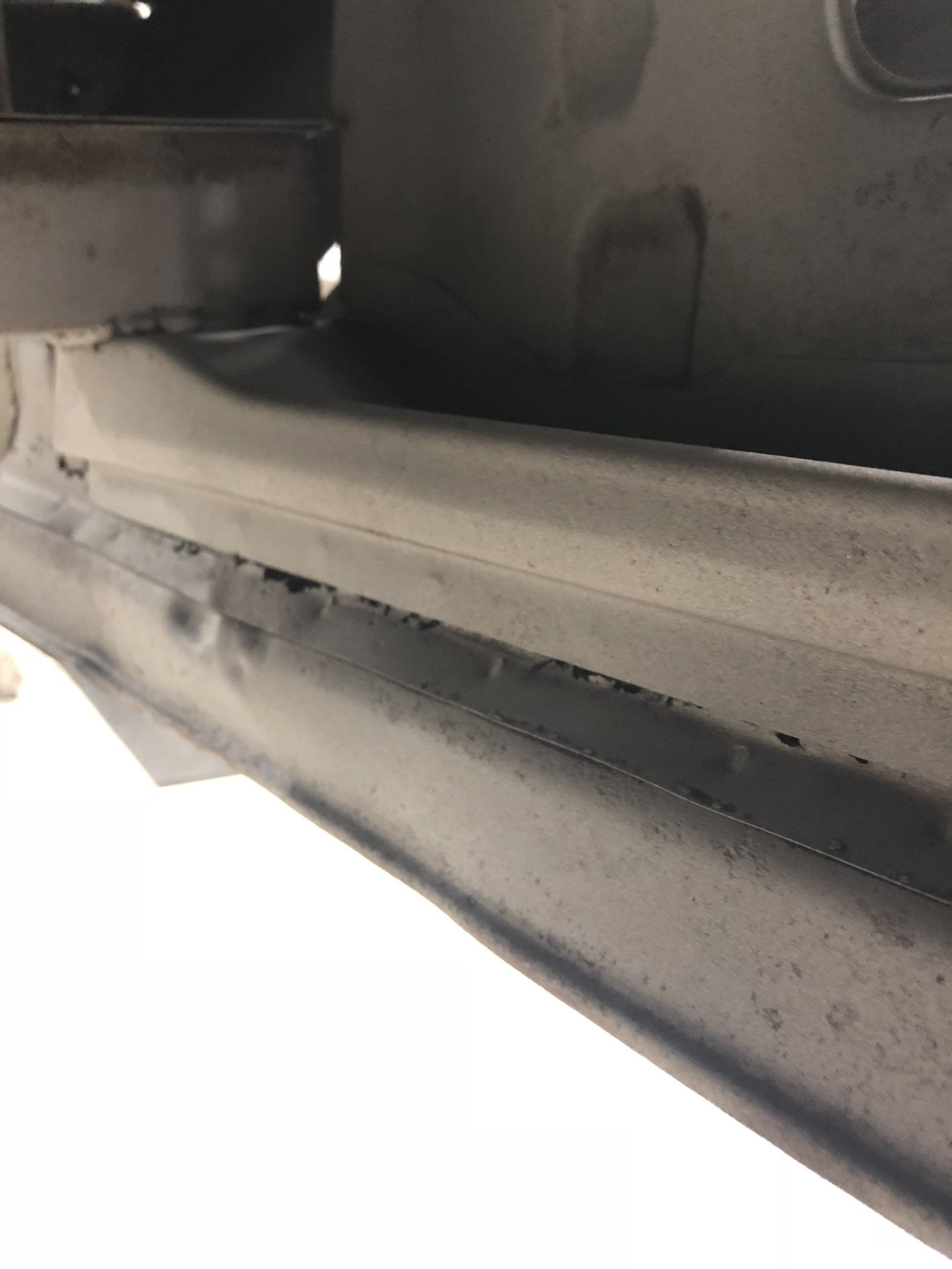 Close-up of a gray metal rail and black surface with a white background below