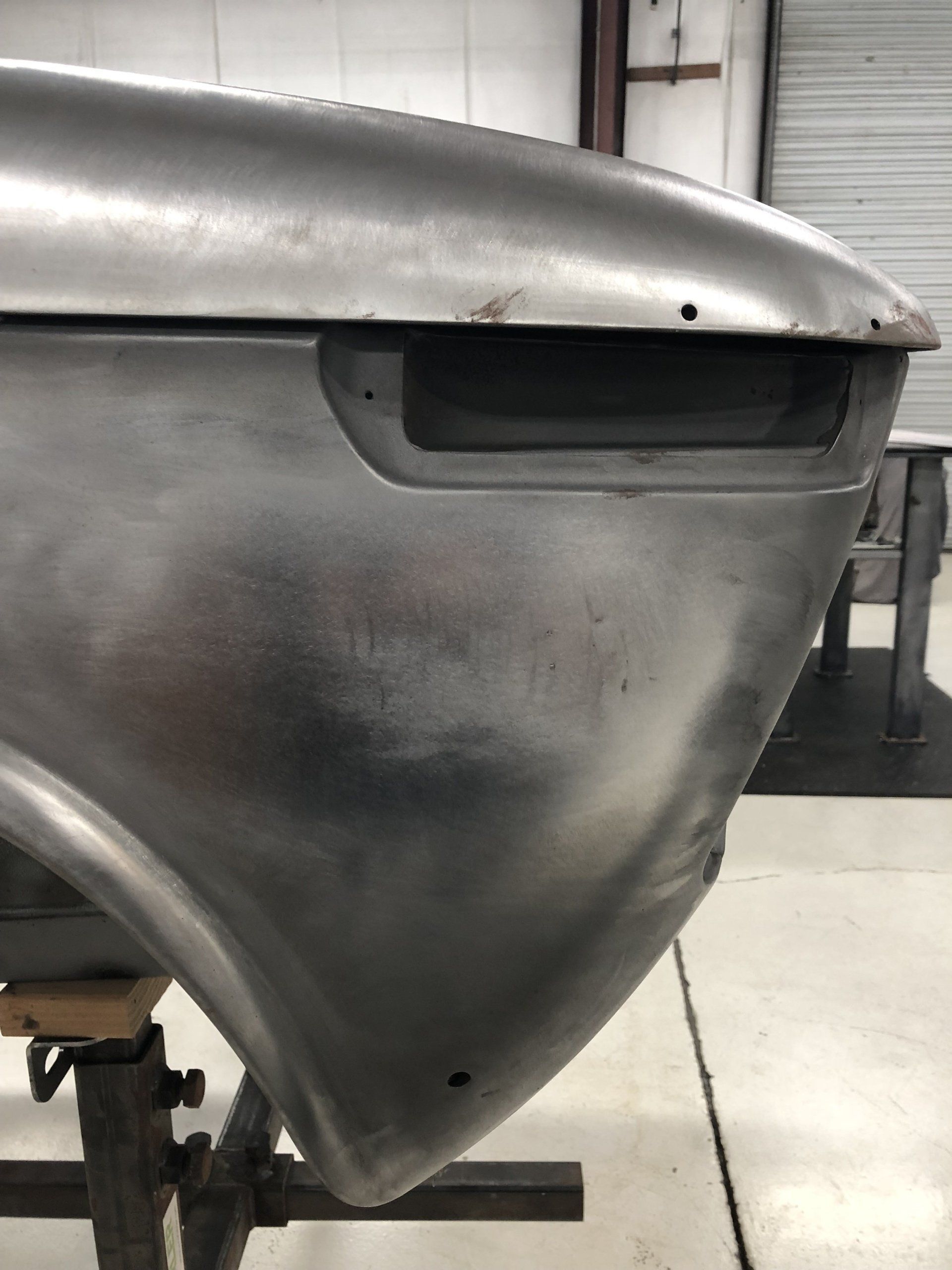 Close-up of a gray metal boat hull in a workshop, showing the bow and top edge.