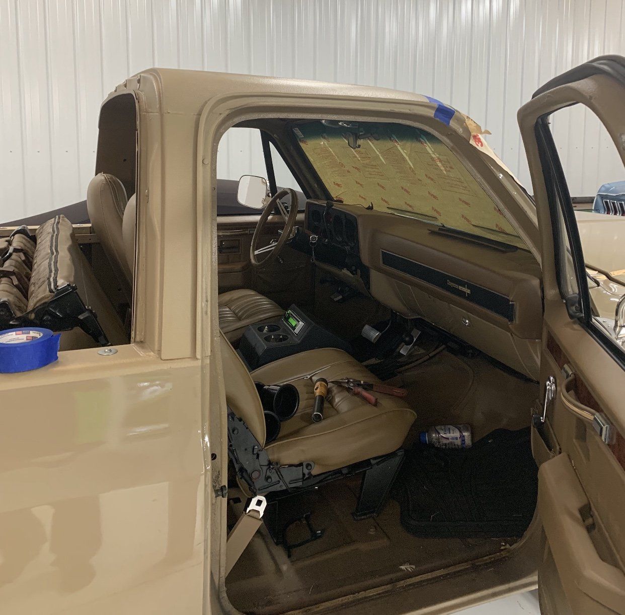 Tan pickup truck with open doors inside a garage or workshop, beige interior visible