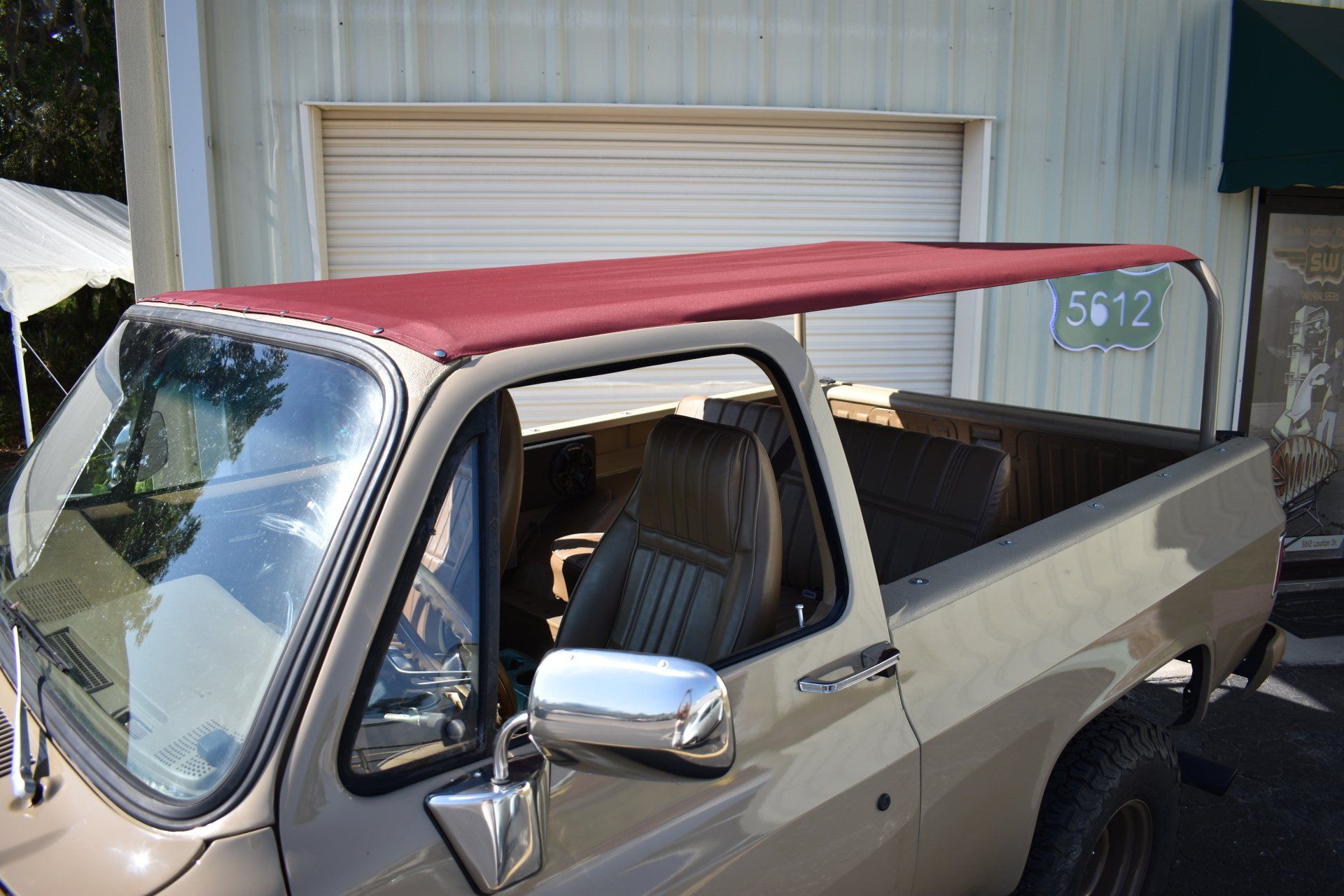 Old pickup truck with red roof parked beside a garage.