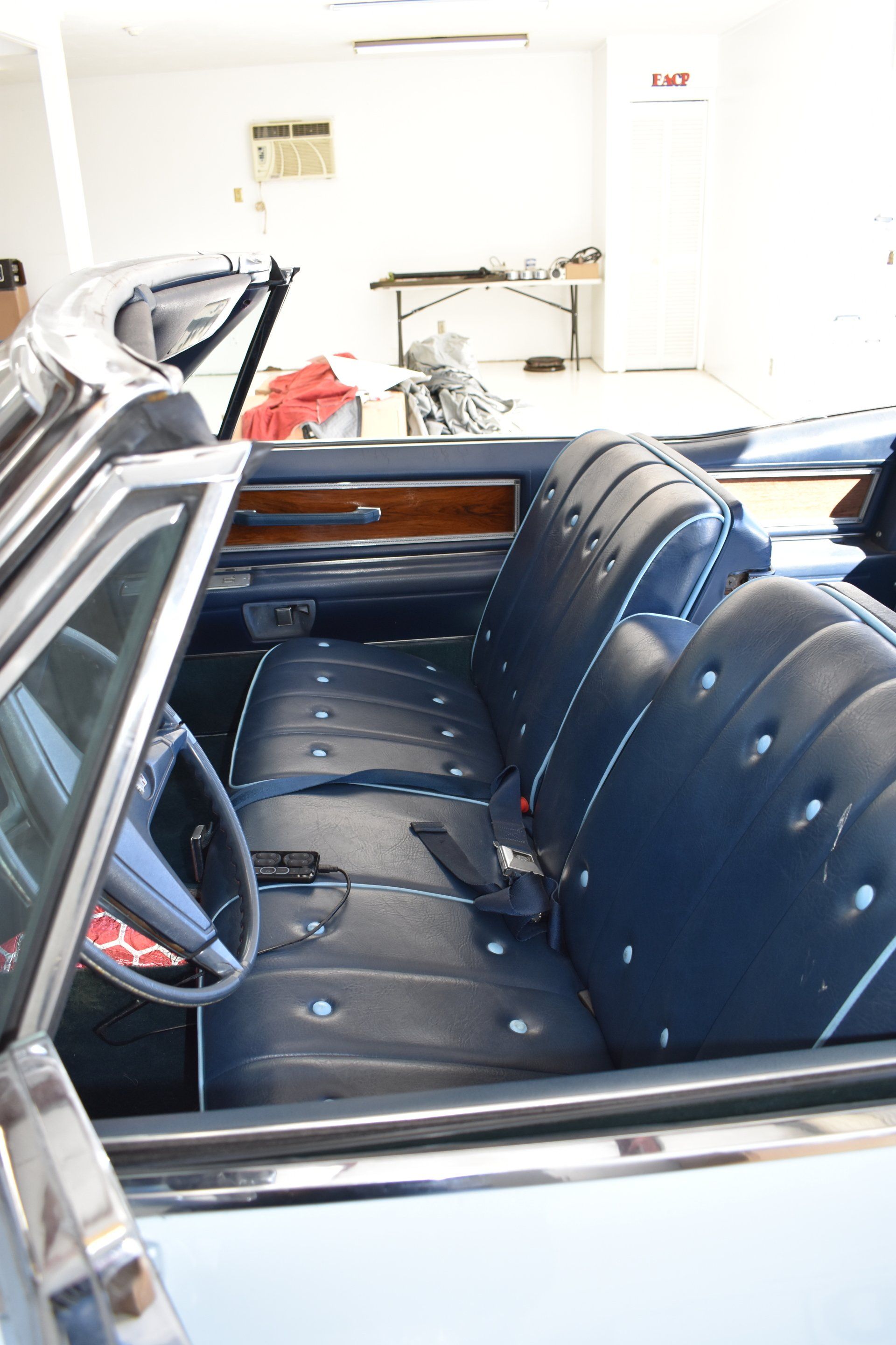 Vintage car interior with blue vinyl bench seats and wood dashboard in a garage