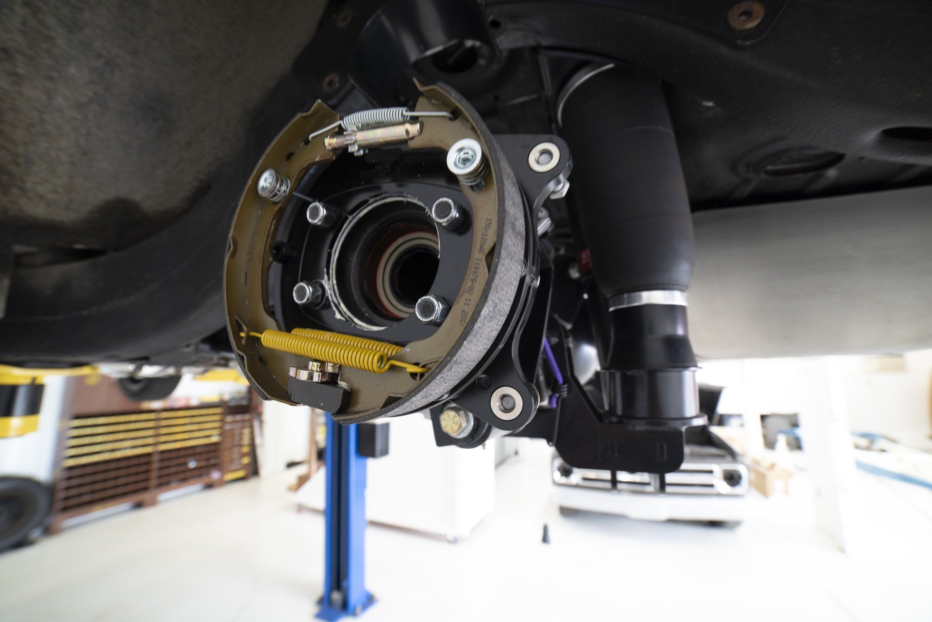 Close-up of a vehicle wheel hub assembly with exposed brake components on a lift
