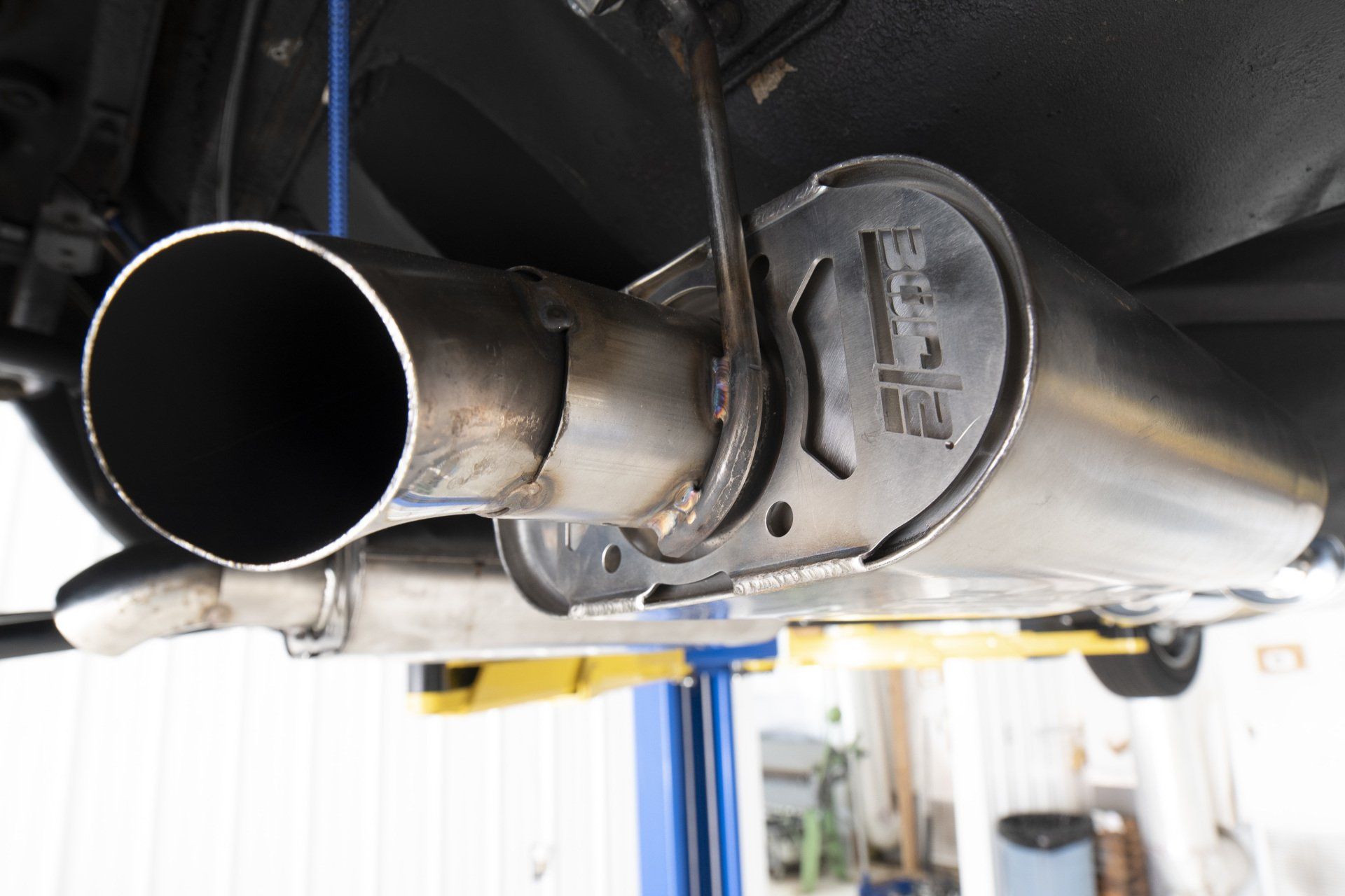 Close-up of a car exhaust pipe and muffler under a vehicle on a lift