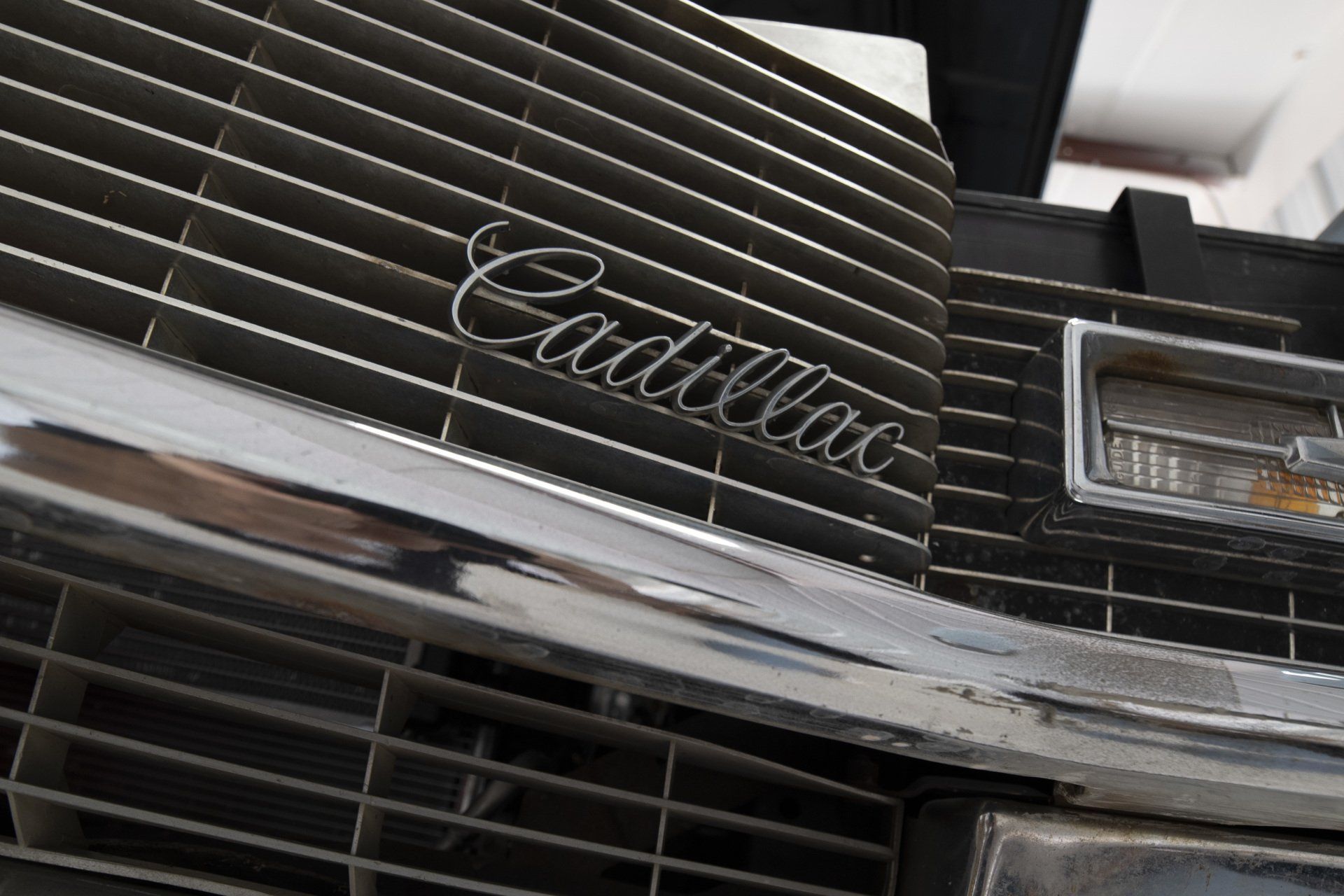 Close-up of a black Cadillac grille and chrome emblem on a classic car front.