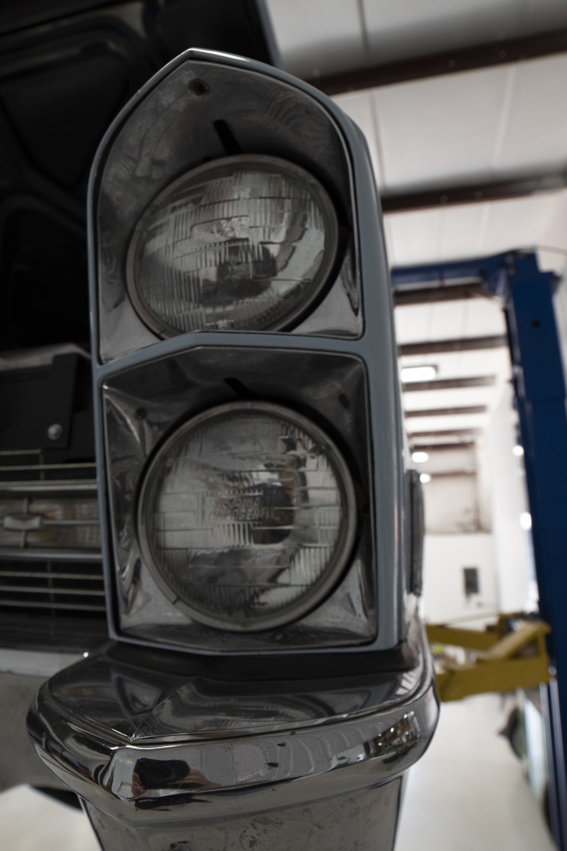 Close-up of a black traffic signal head with two round lenses in an indoor workshop.