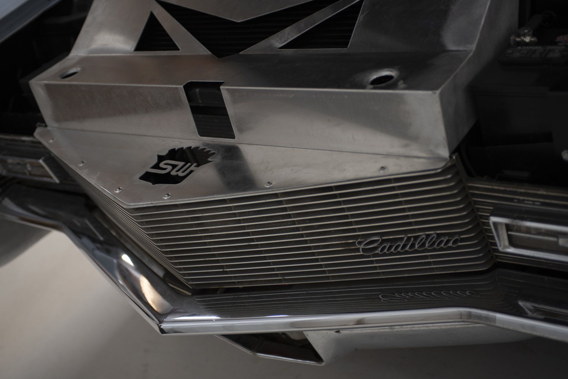 Close-up of a silver Cadillac steering wheel and dashboard trim with black ribbed accents