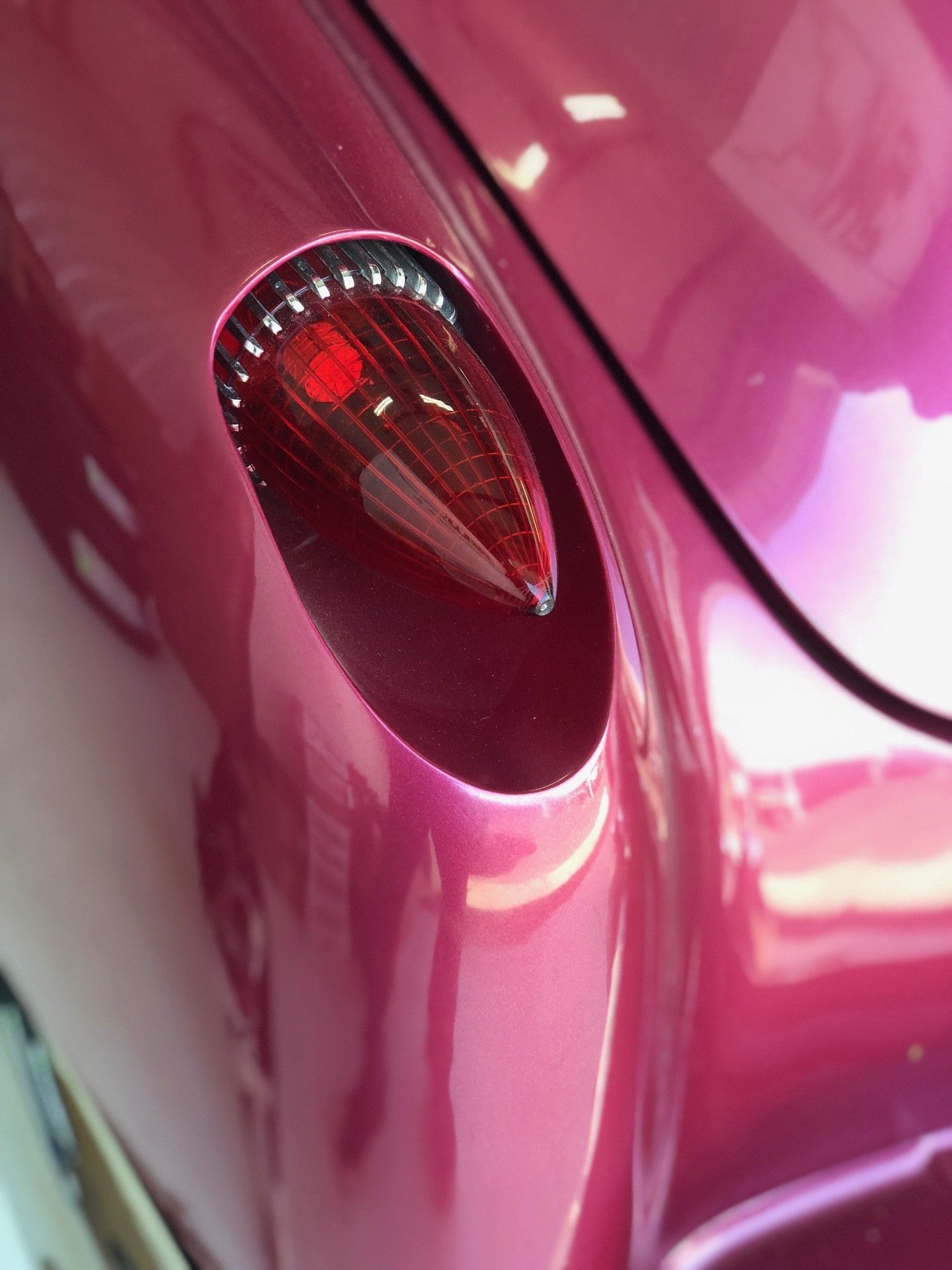 Close-up of a pink car’s rear taillight and curved body panel