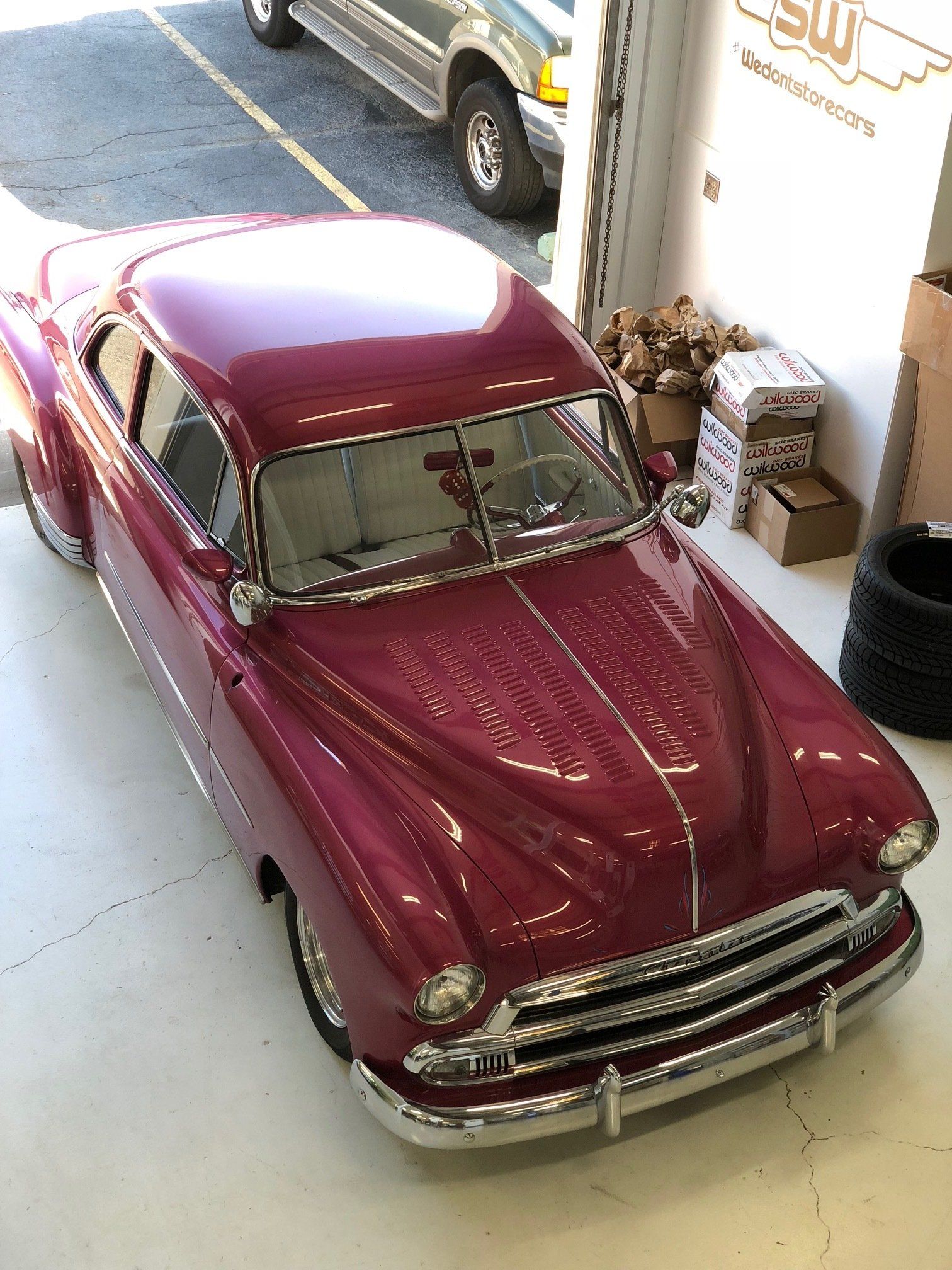 Maroon vintage car parked indoors near an open garage door