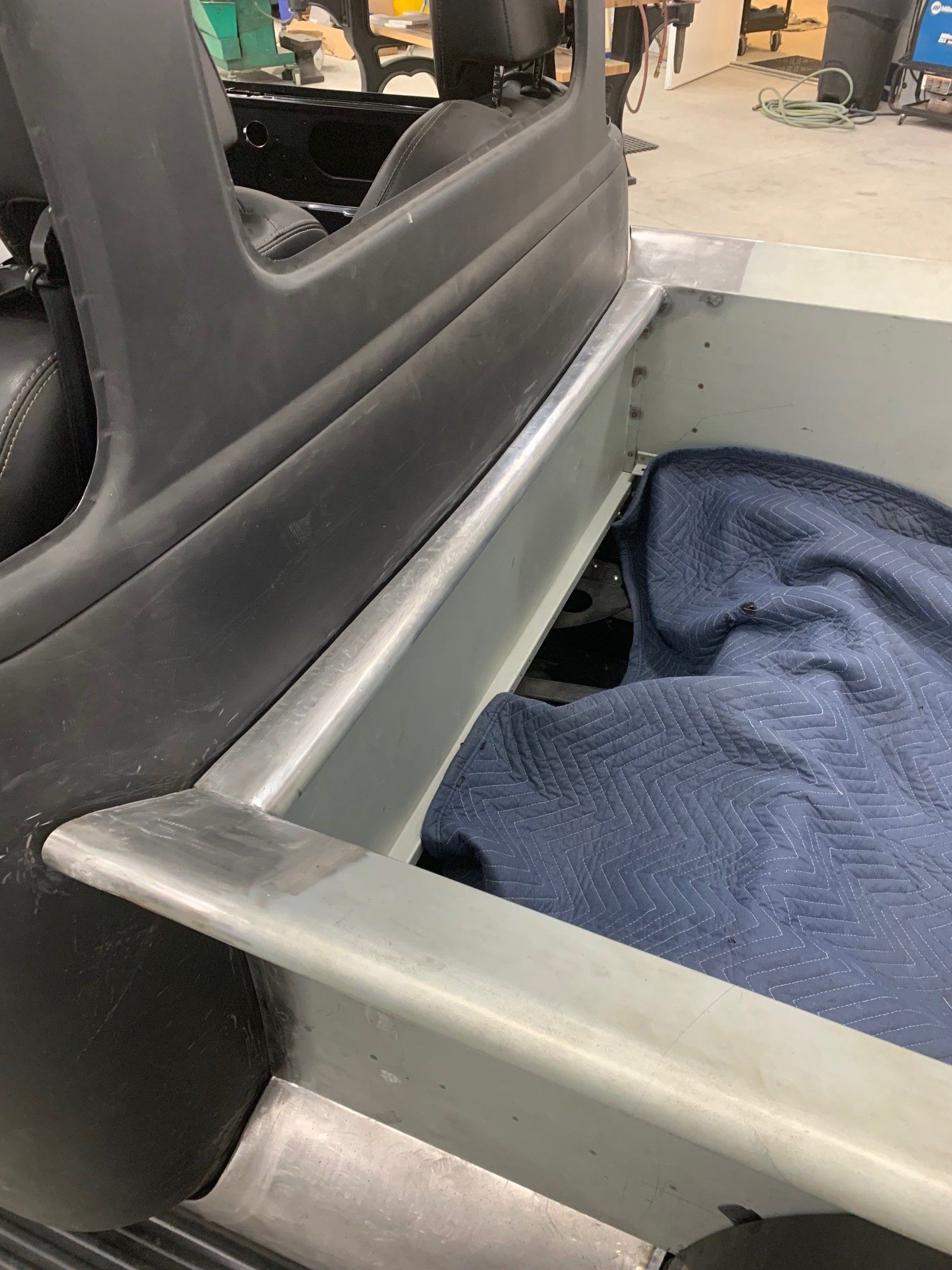Gray wheelchair with black seat cushion and blue blanket in a public indoor space