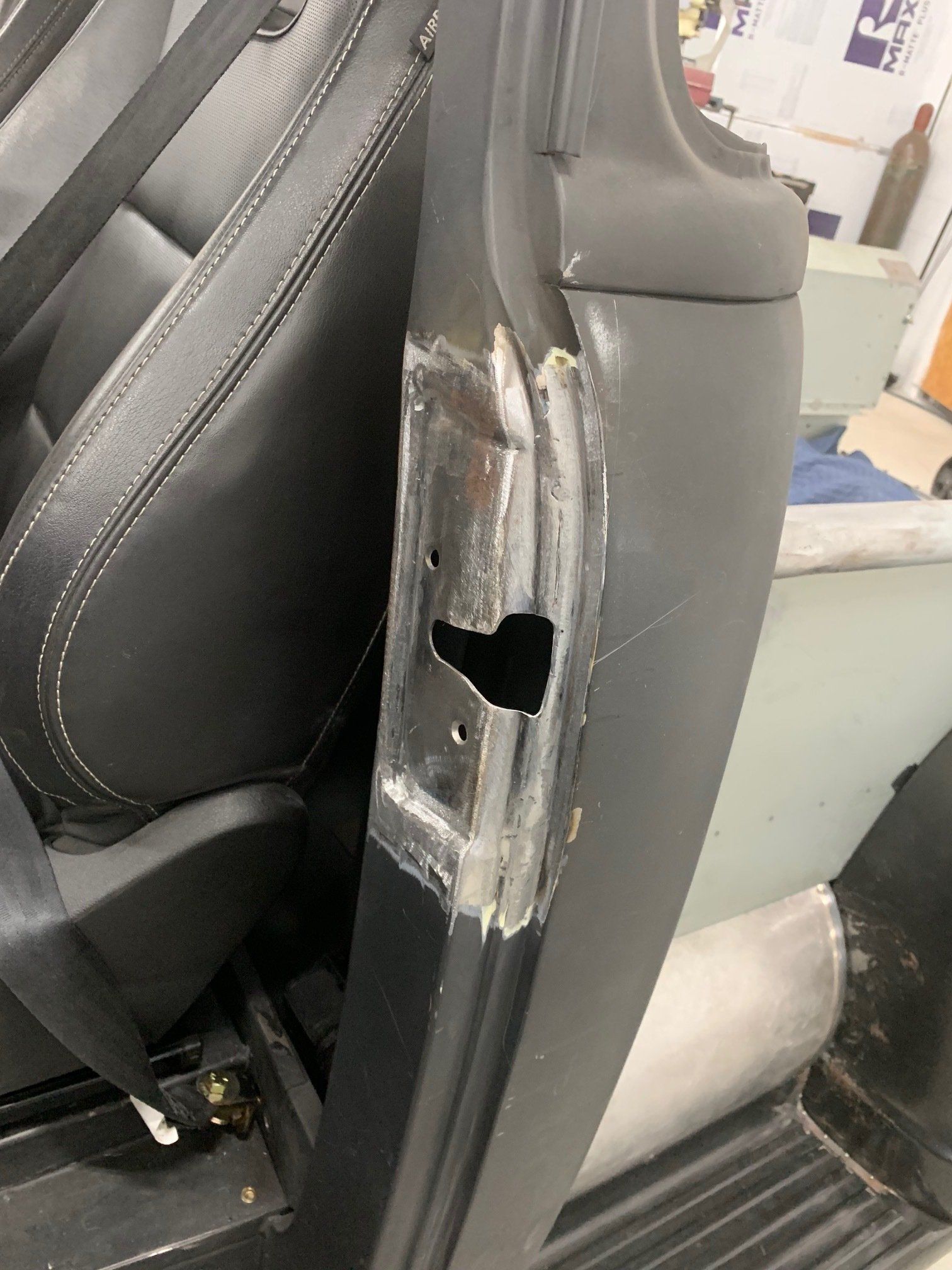 Damaged car door pillar with exposed metal and a hole near the seat.