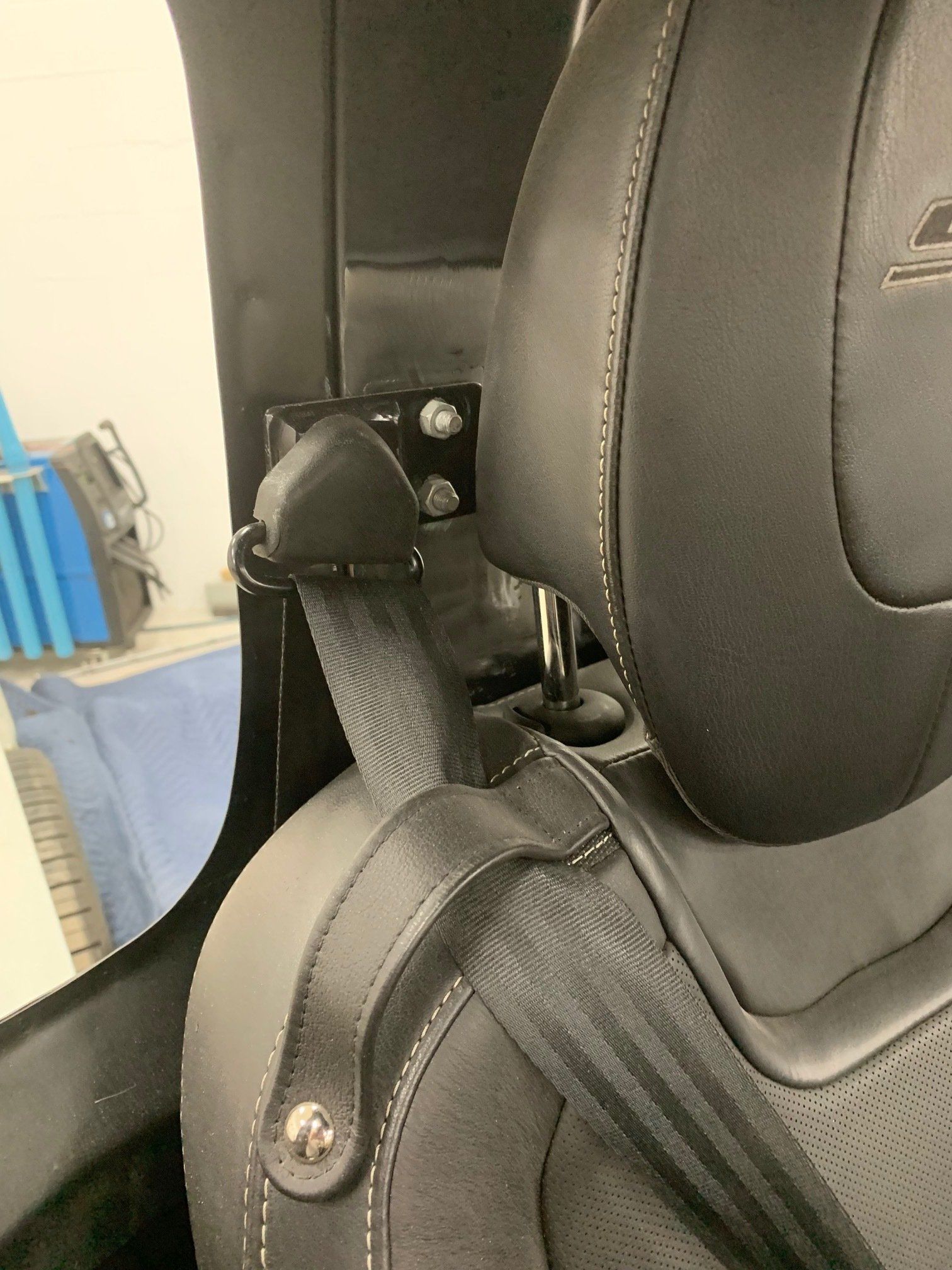 Close-up of a black car seat belt buckled beside a black leather seat.
