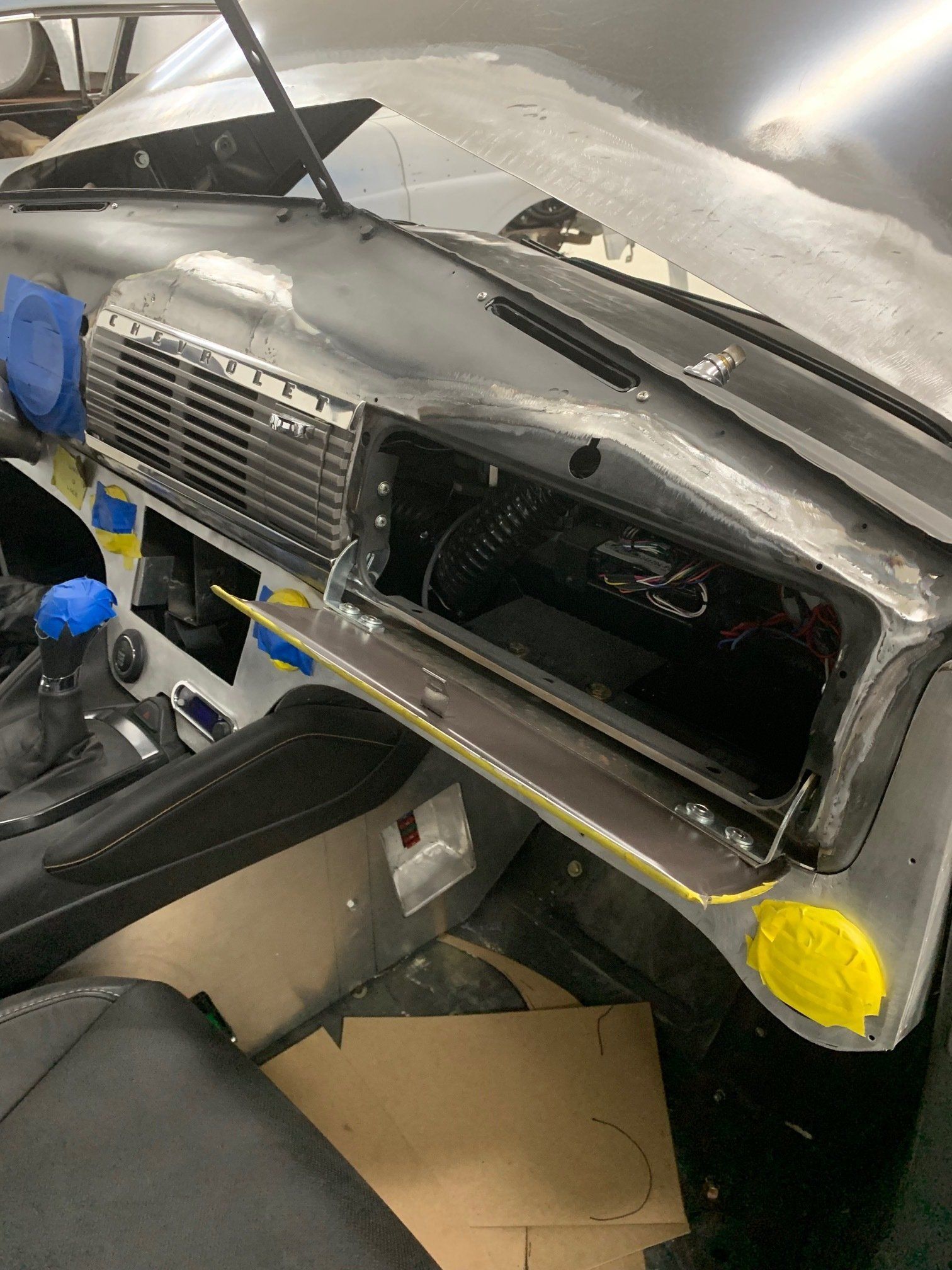 Damaged car front end with exposed internal components and open hood in a workshop