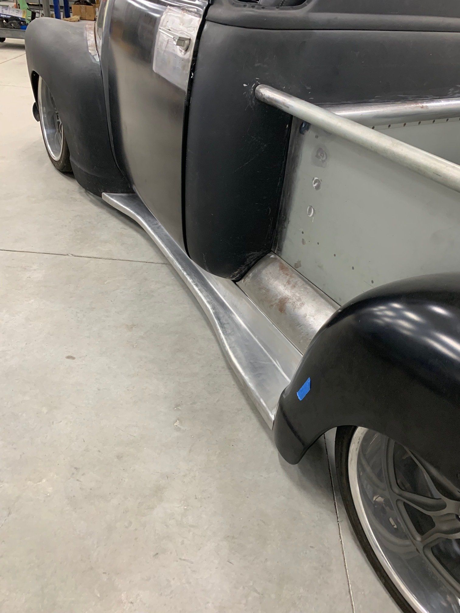 Close-up of a silver vintage car side with black fender skirts and a chrome running board.