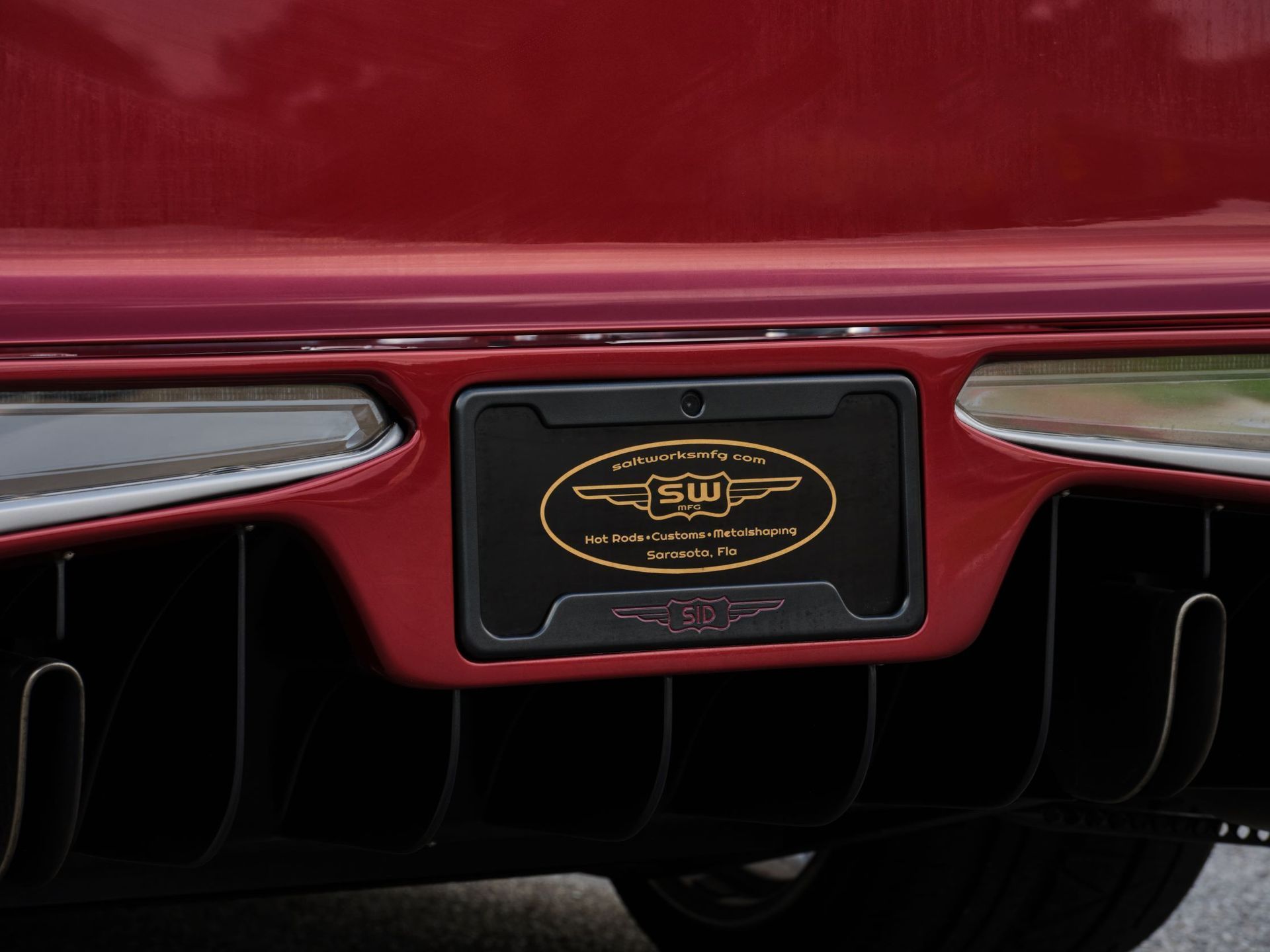 Rear view of a red luxury car with a black and gold license plate and twin exhaust vents