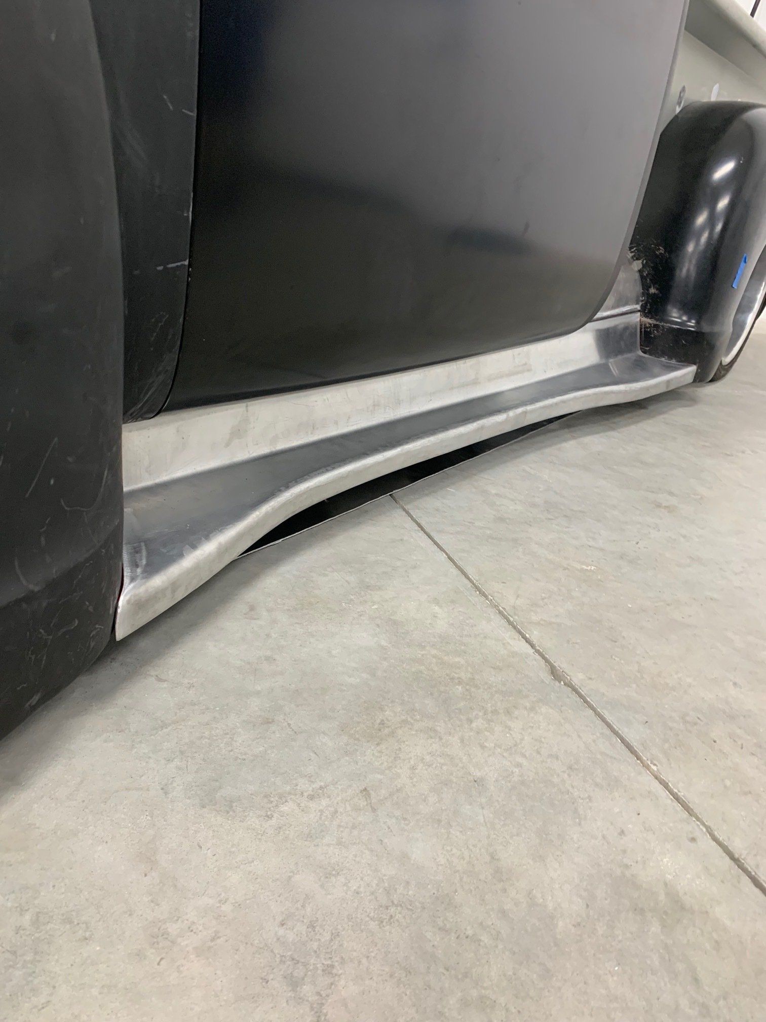 Bent metal car rocker panel scraping the concrete floor indoors