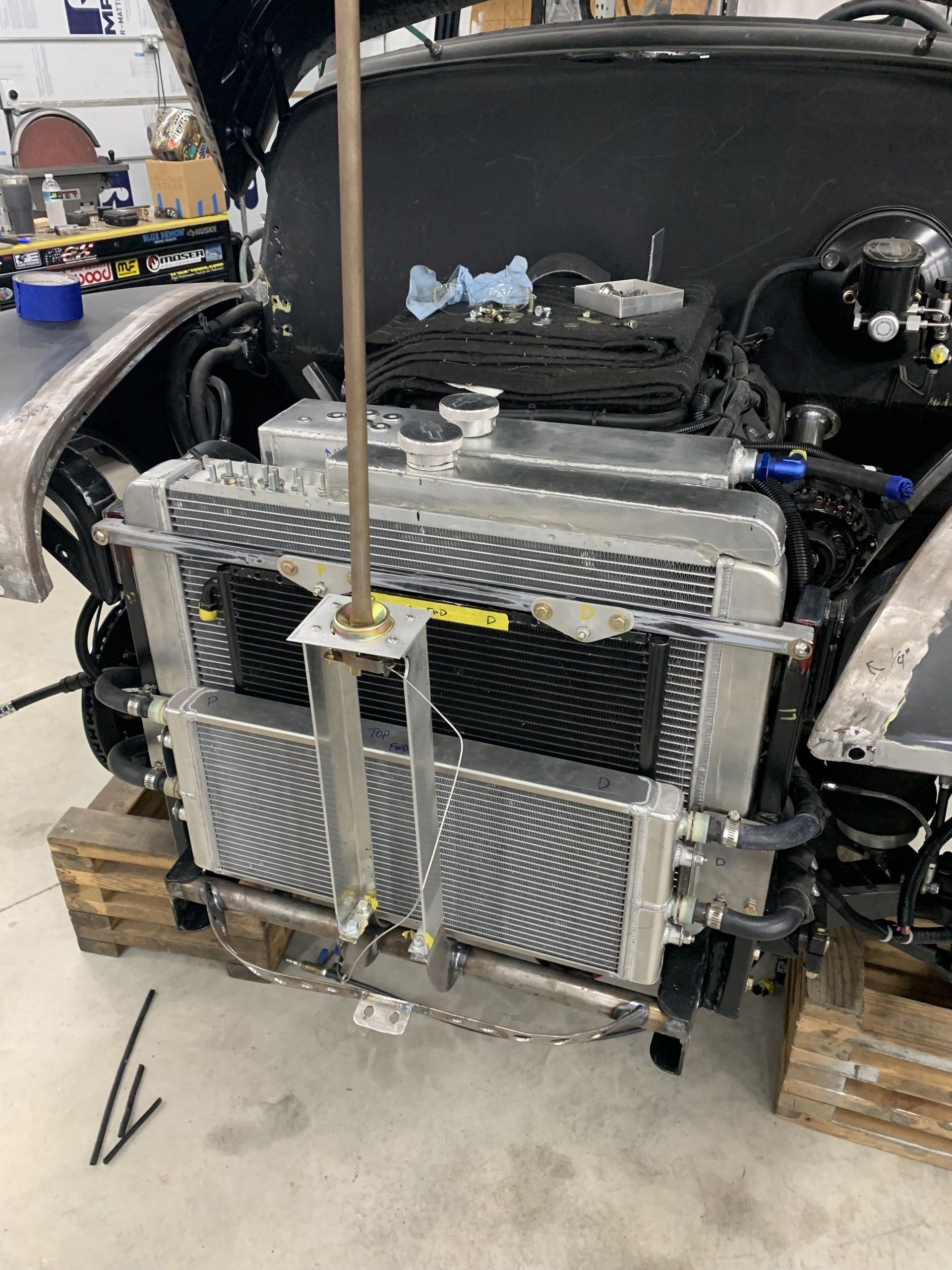 Custom car radiator and front cooling assembly mounted on a vehicle frame in a garage
