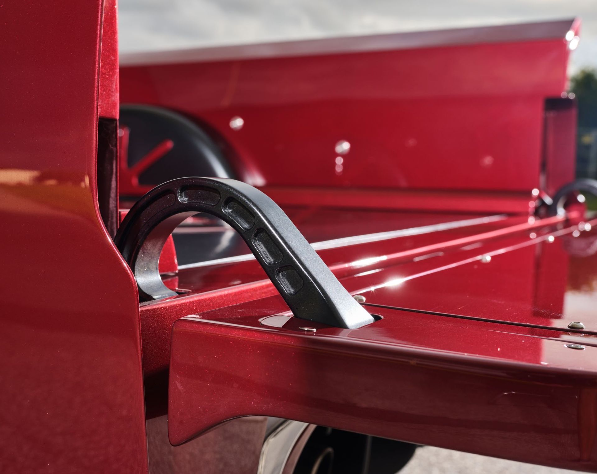 Close-up of a red metal machine frame with a black curved handle or cable brace.