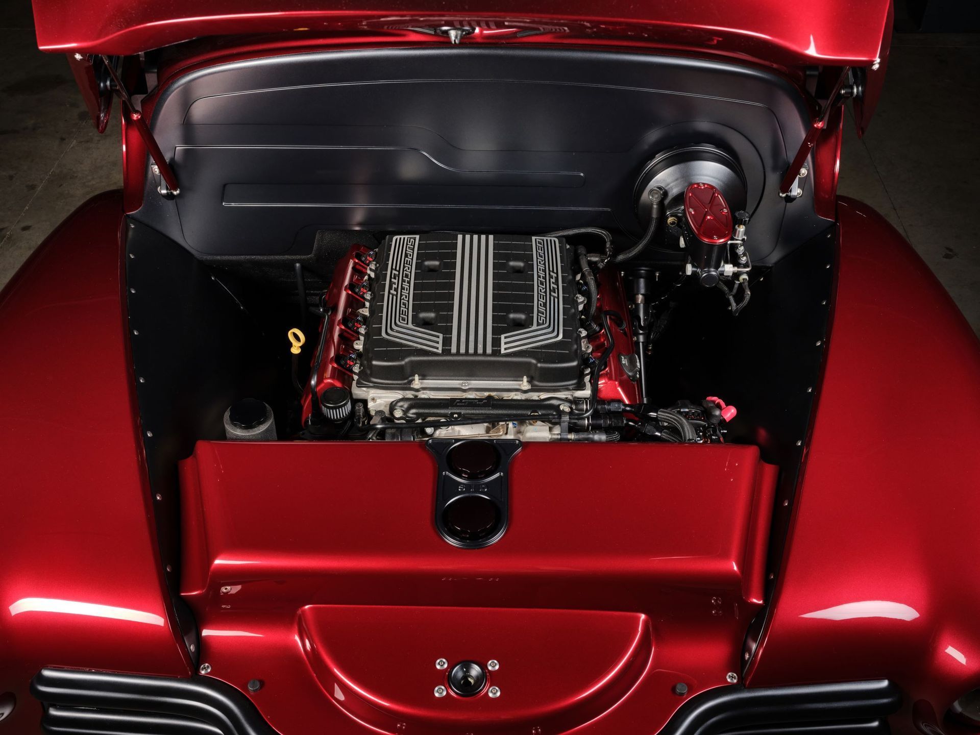 Open red car trunk with a custom engine bay and polished mechanical parts
