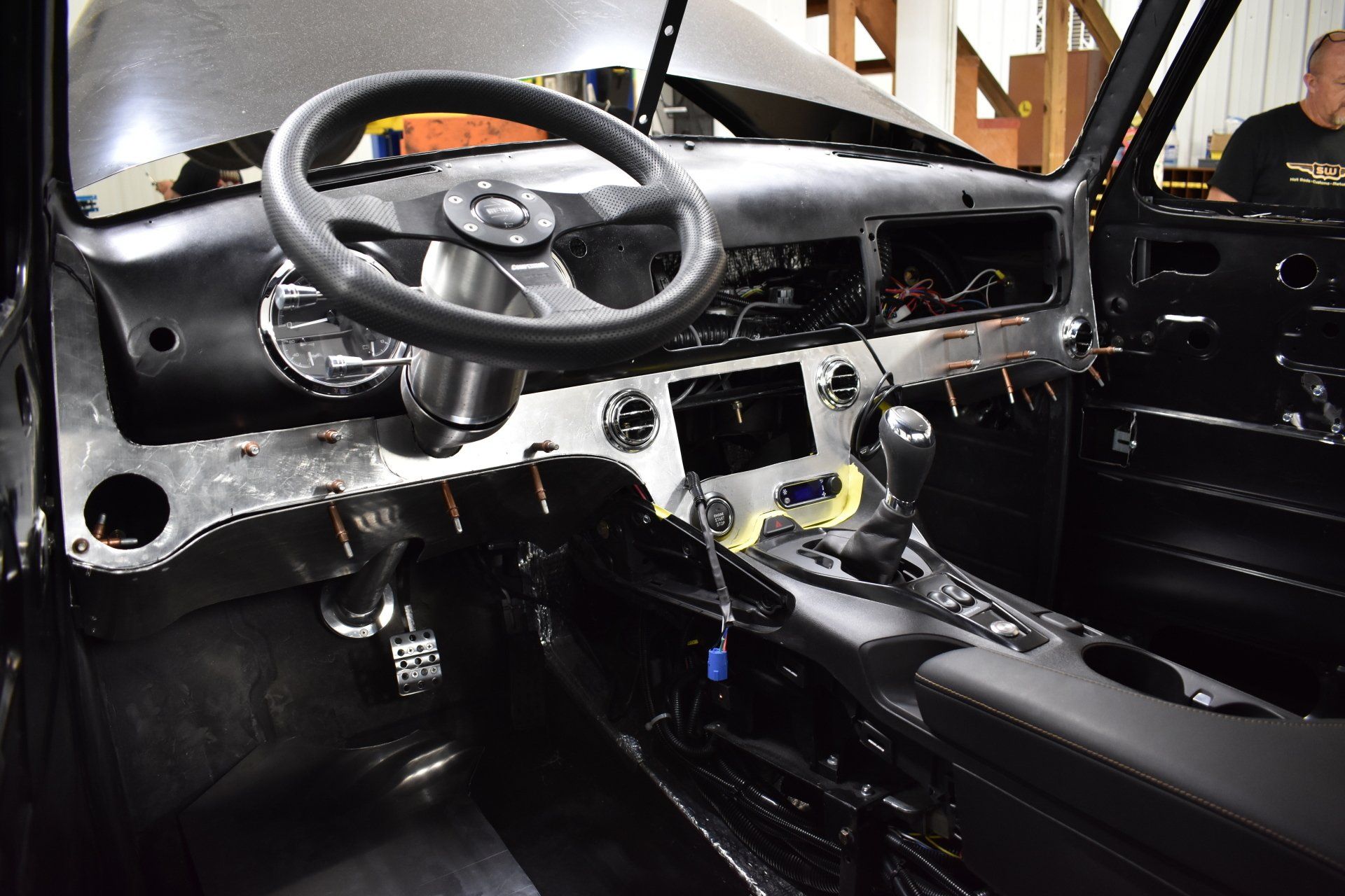Interior of a stripped black car, showing the steering wheel, dashboard, and center console.