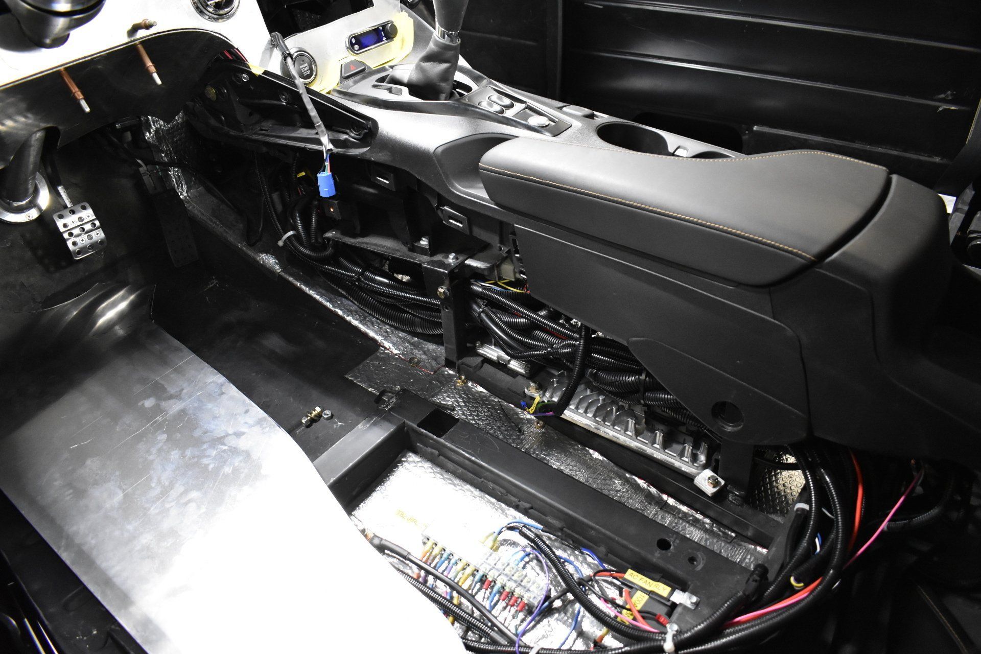 Car interior stripped to bare metal, showing exposed wiring and center console area