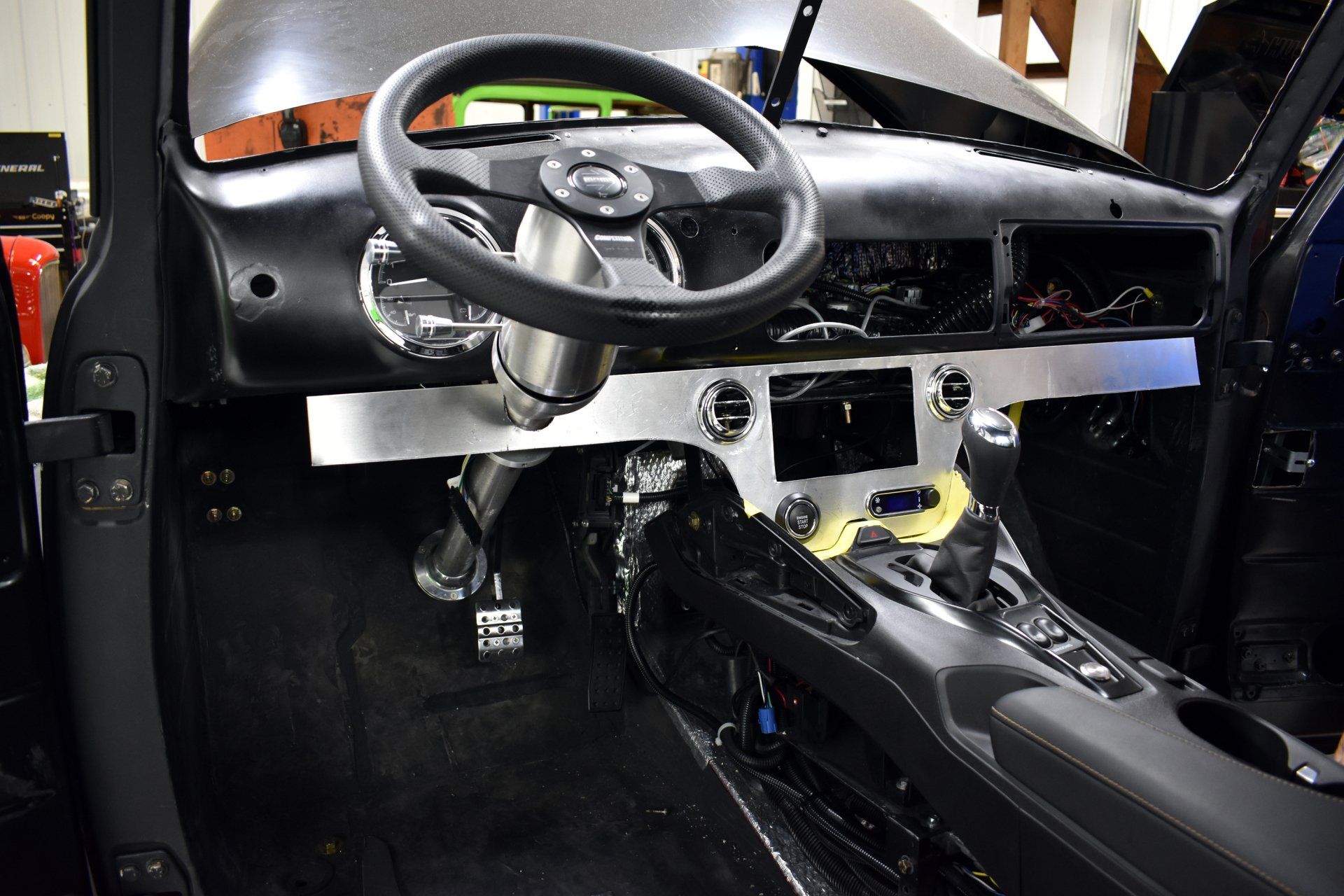 Car interior with exposed dashboard, steering wheel, and center console, stripped for repair or customization