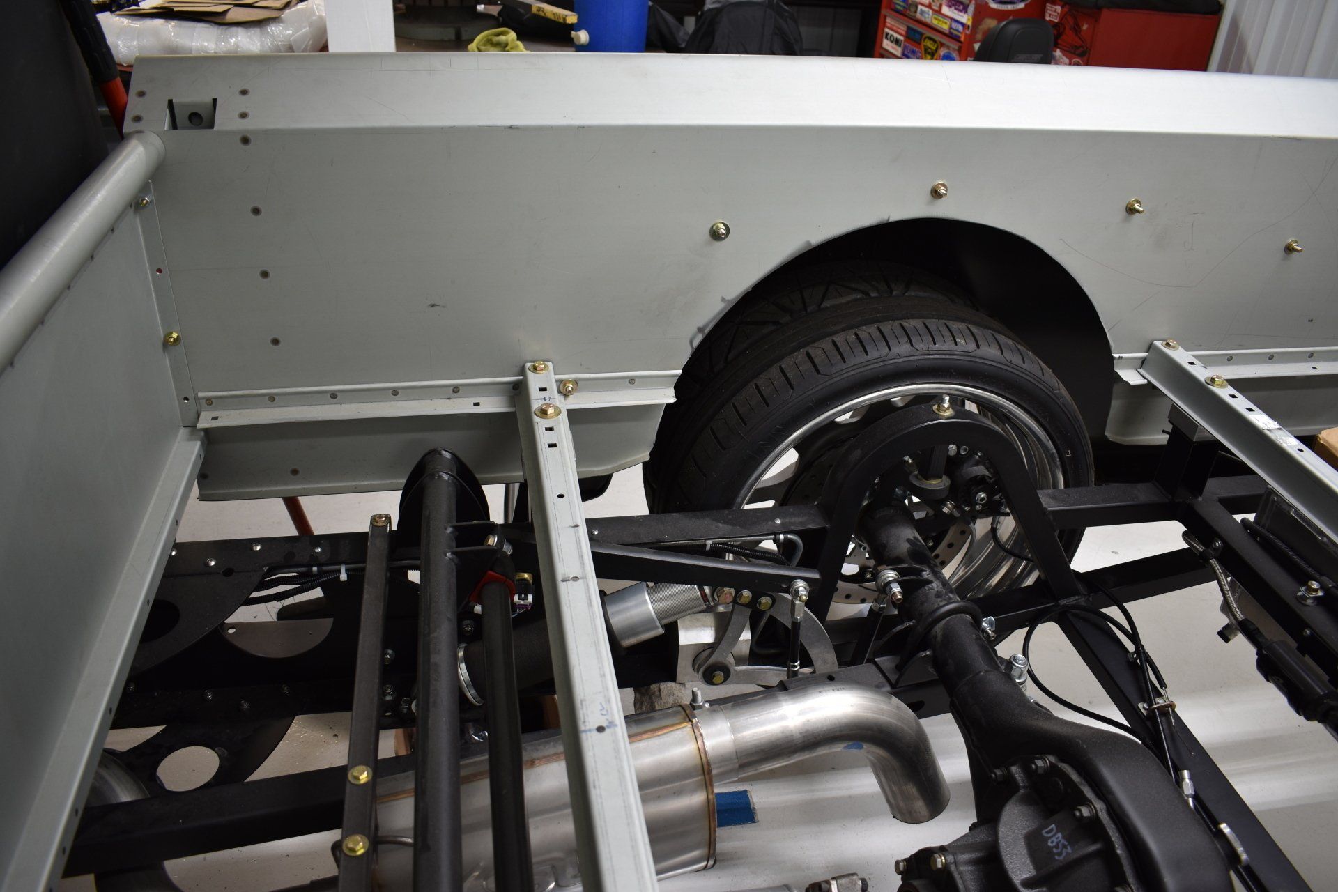 Exposed vehicle chassis with rear wheel and suspension in a garage or workshop