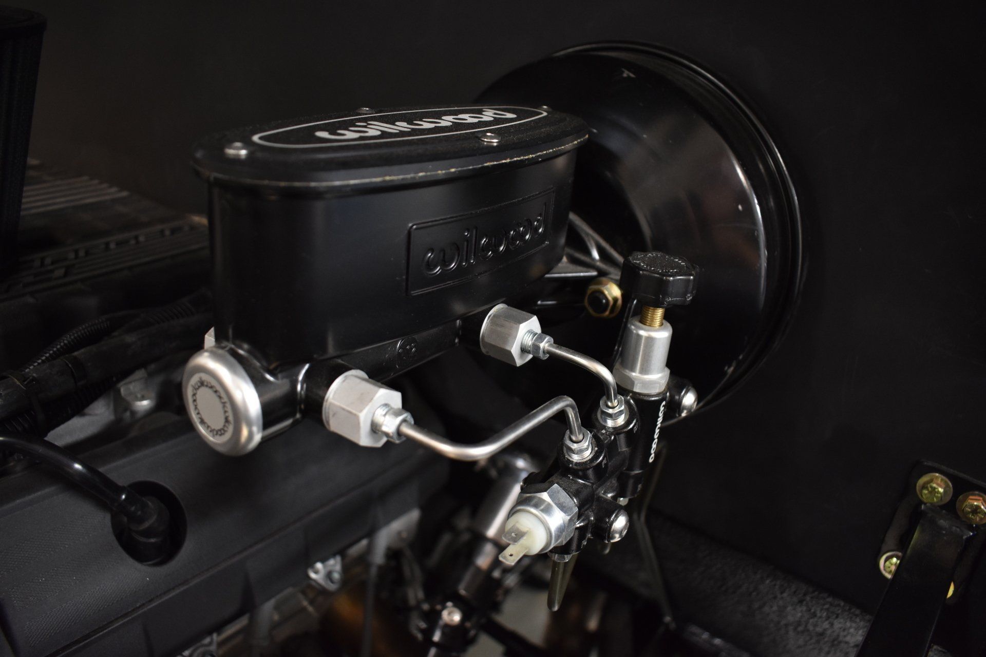 Black vehicle brake booster and master cylinder assembly inside a dim car cabin