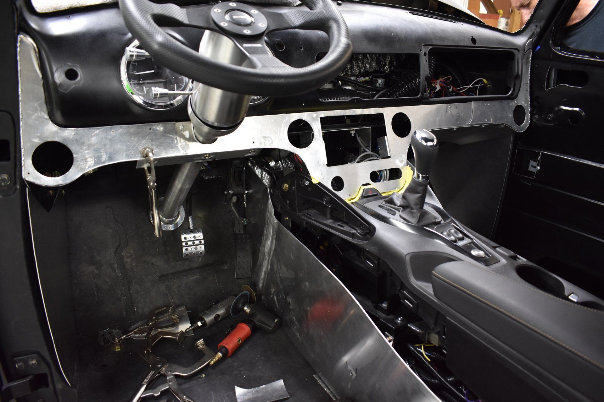 Car interior with exposed dashboard wiring and a partially stripped center console during repair