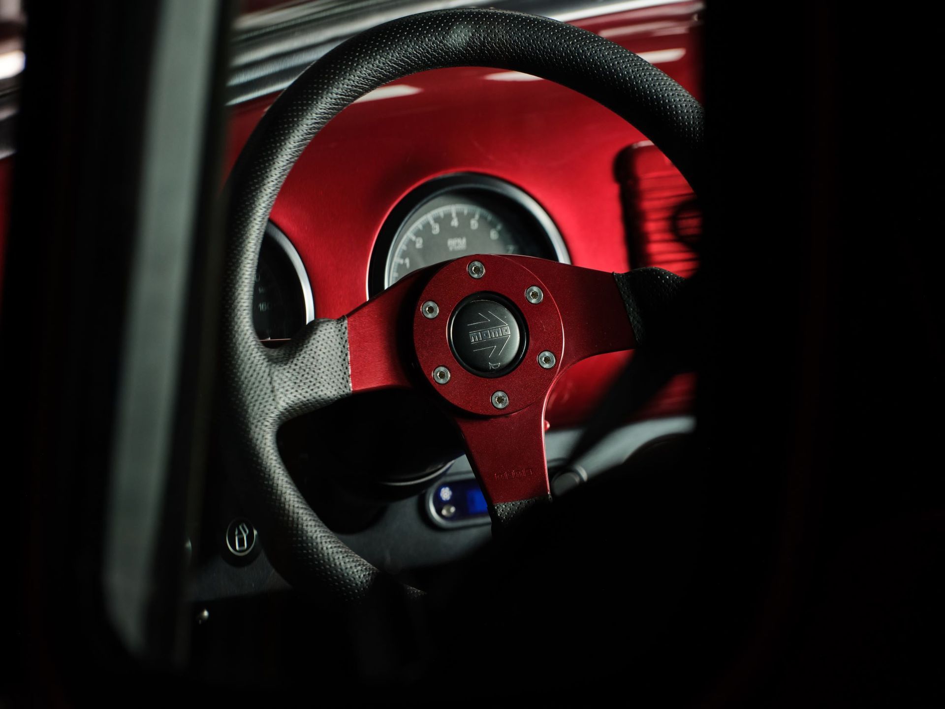 Close-up of a red racing steering wheel and dashboard inside a car