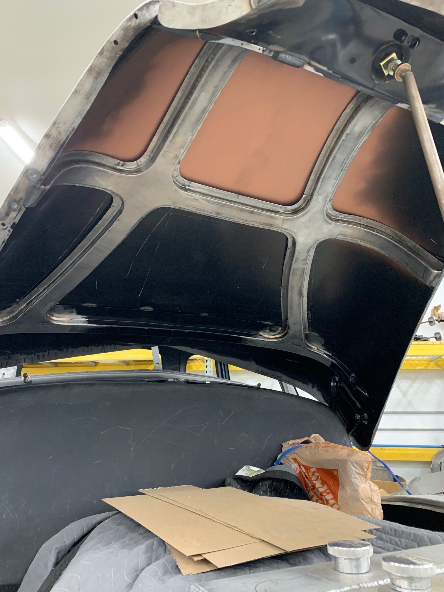 Open car hood with exposed underside and cardboard sitting in the engine bay