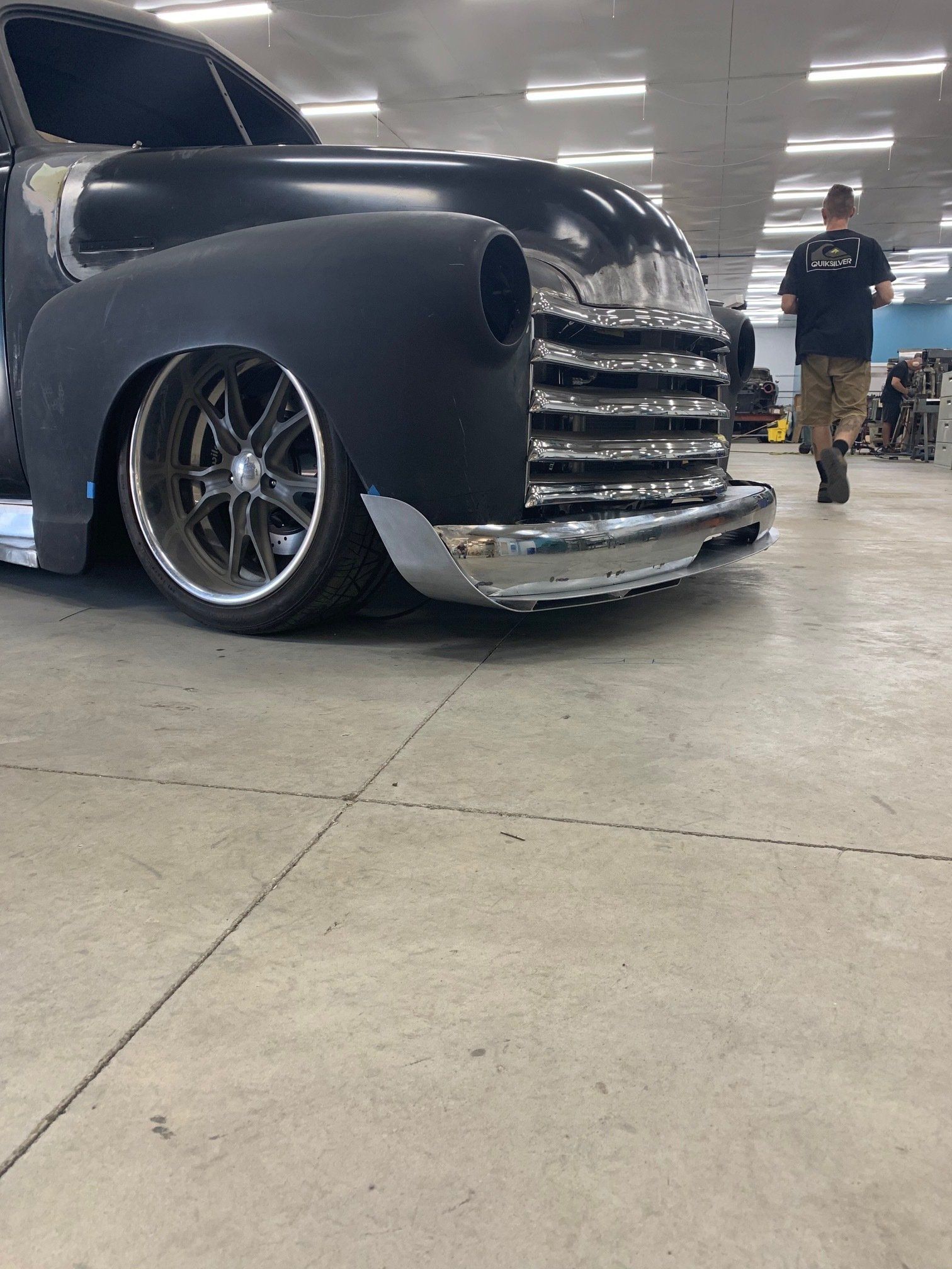 Black classic custom pickup truck with chrome grille in a garage, low-angle view