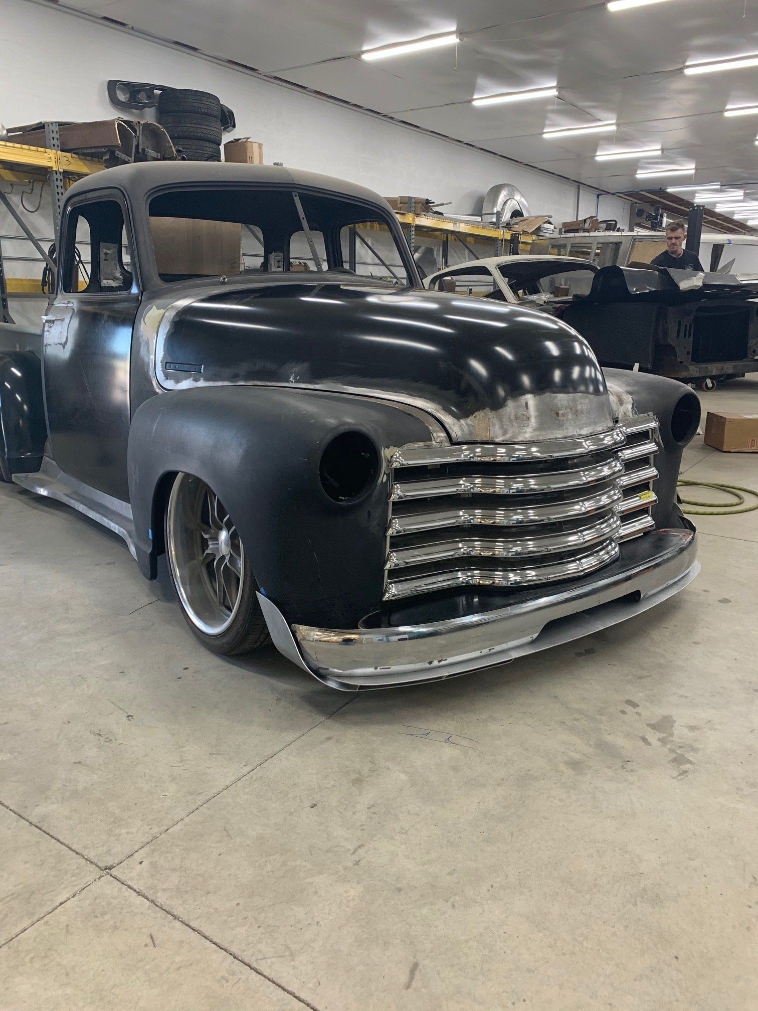 Black vintage pickup truck with chrome grille in an indoor garage or showroom