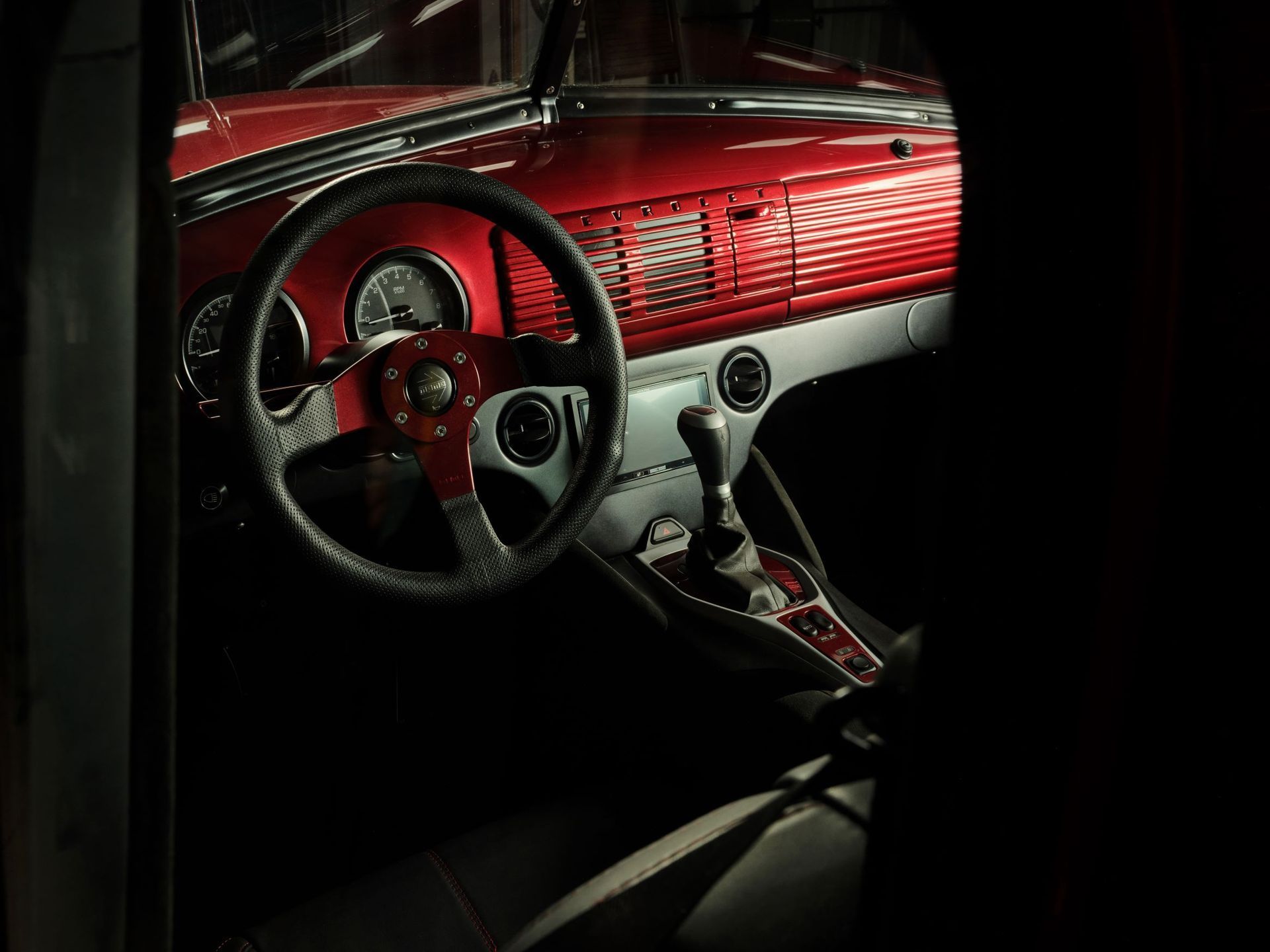 Vintage red car interior with steering wheel, dashboard, and manual gear shift
