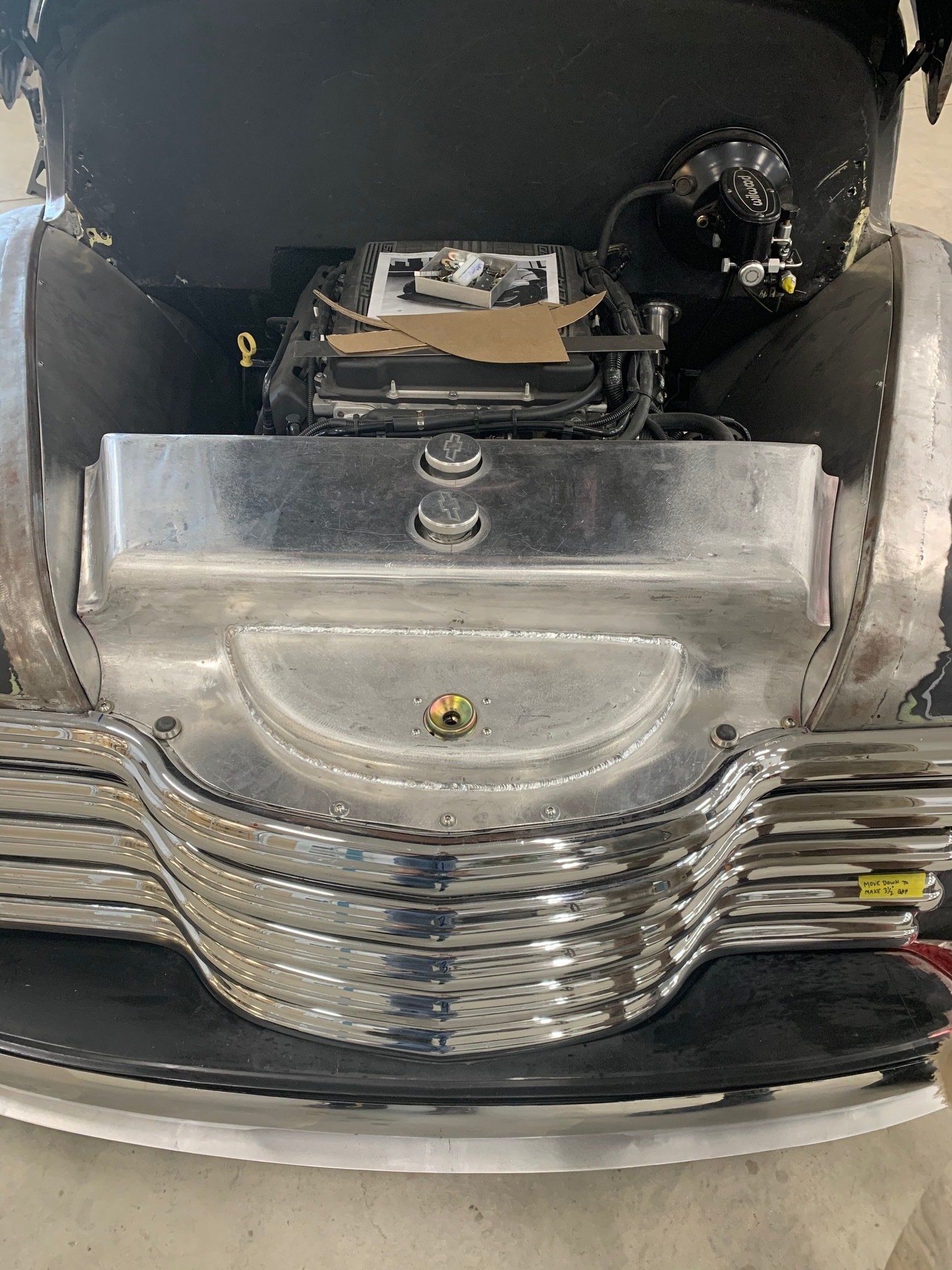 Open car trunk showing a chrome engine compartment and black interior panels