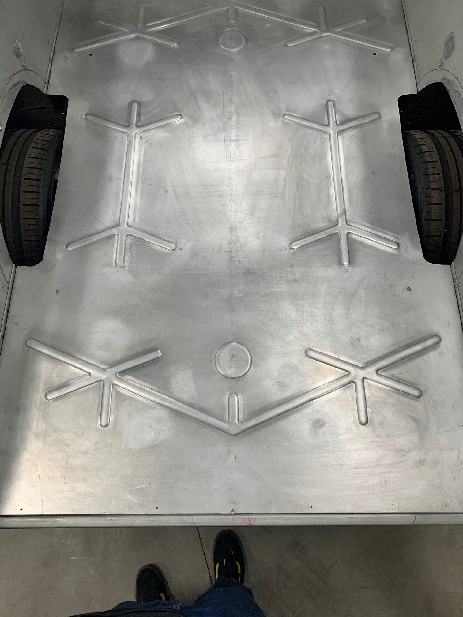 Large metal platform with symmetrical white structural pieces and wheels on both sides, viewed from above