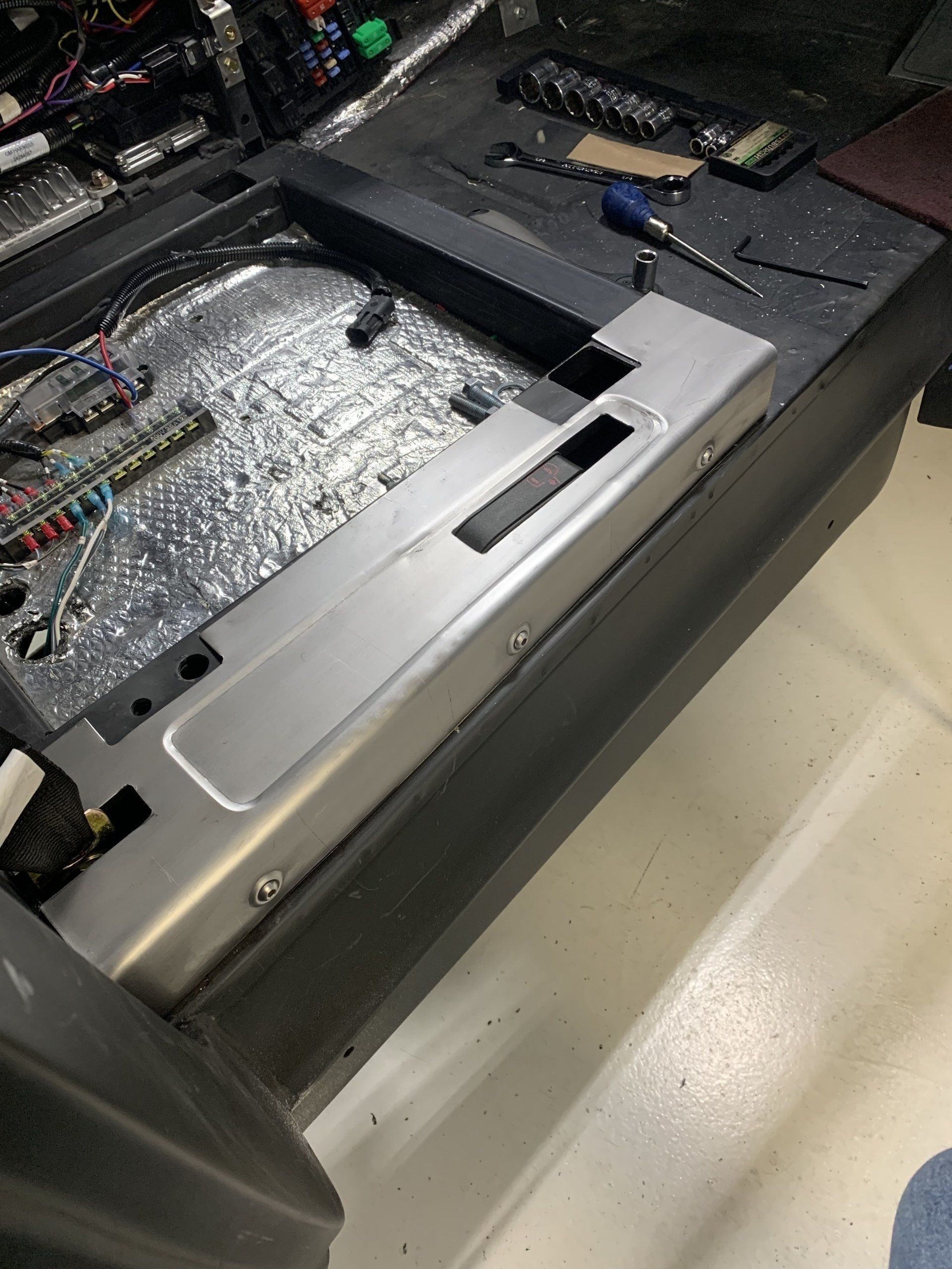Open machinery compartment with silver insulation and black casing on a factory floor