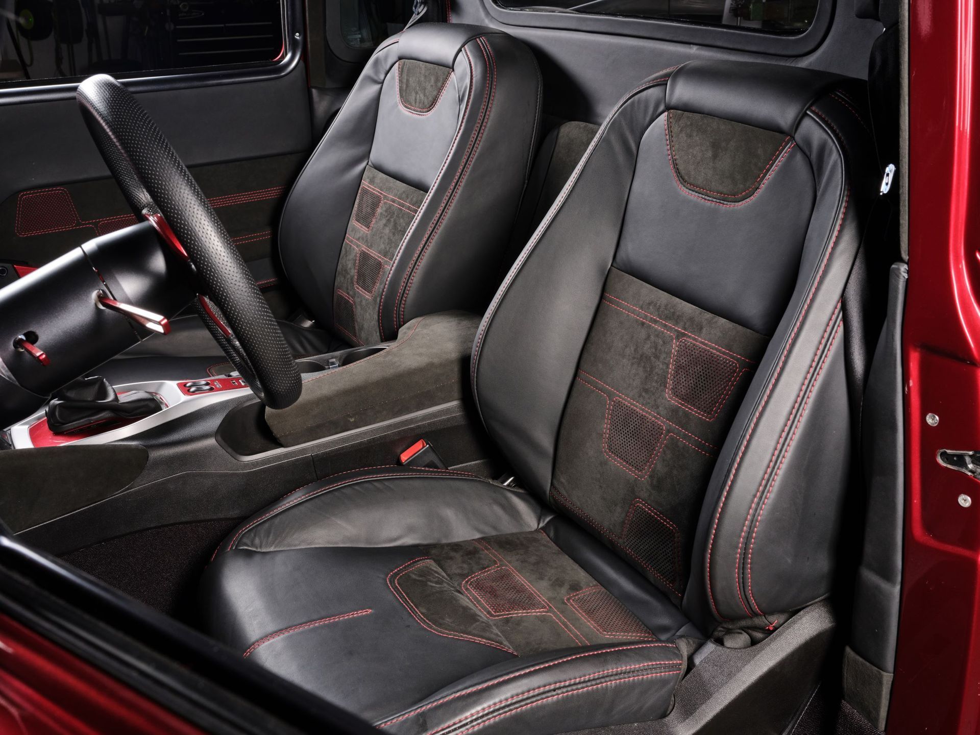 Two black racing-style car seats with red stitching inside a red vehicle interior