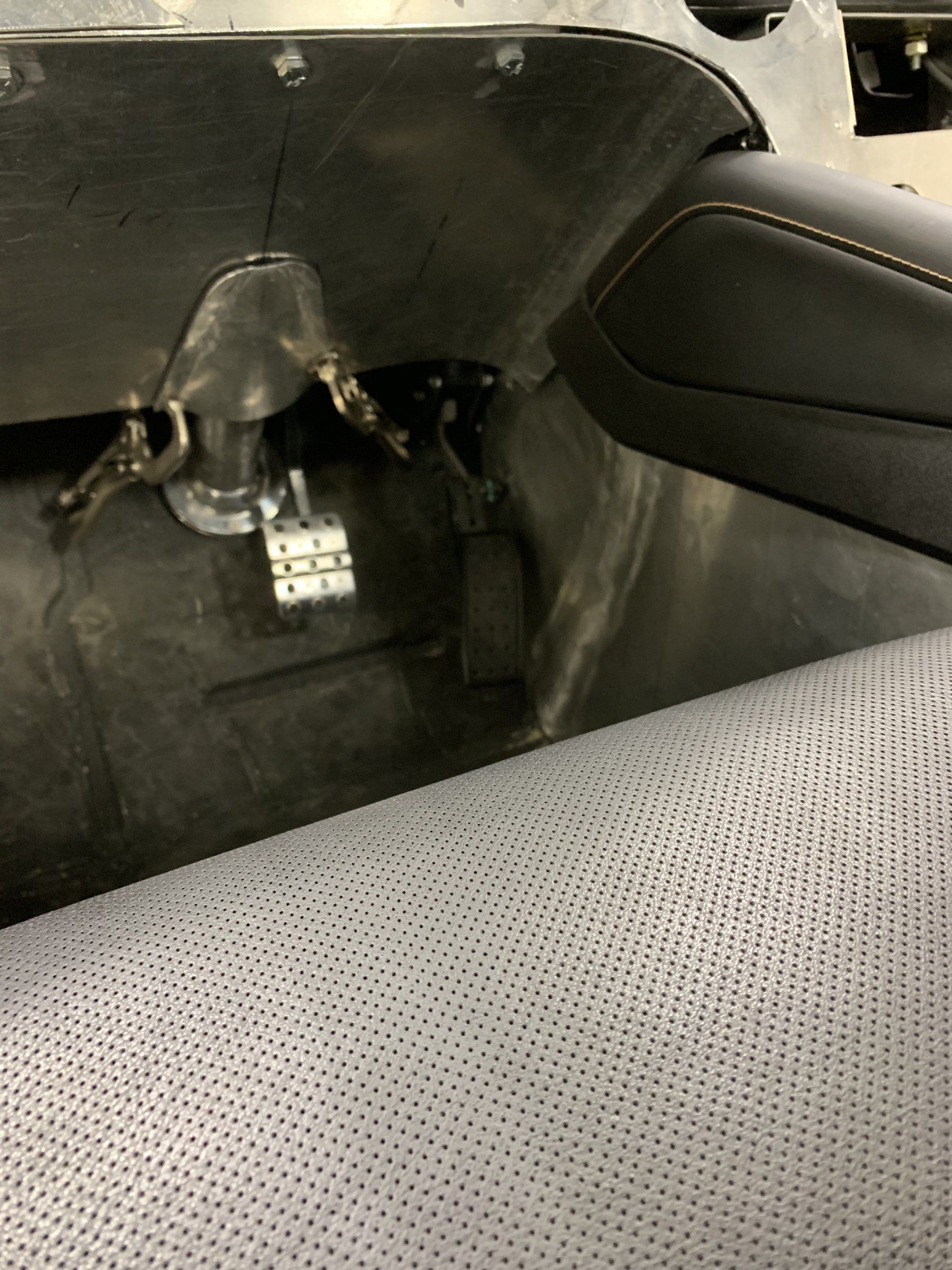 Black vehicle interior with exposed wiring and a detached panel near the rear seat.