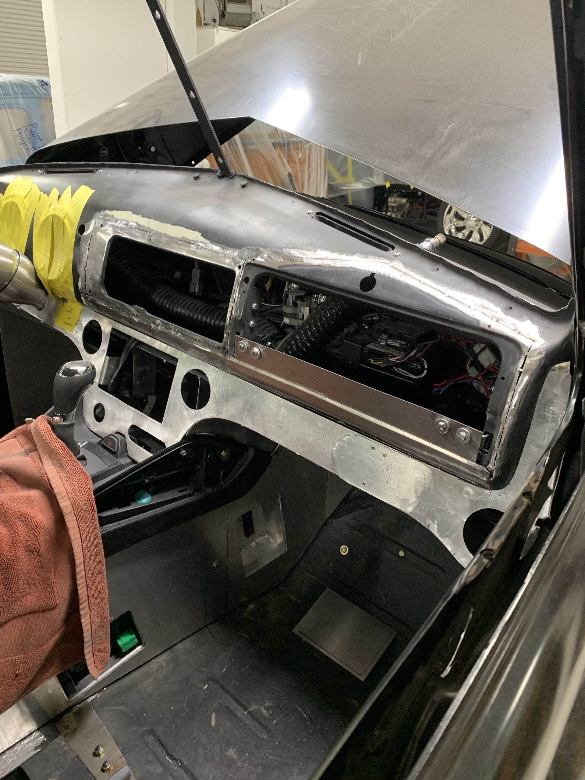 Old car interior stripped to bare metal, showing dashboard opening and exposed floor area.