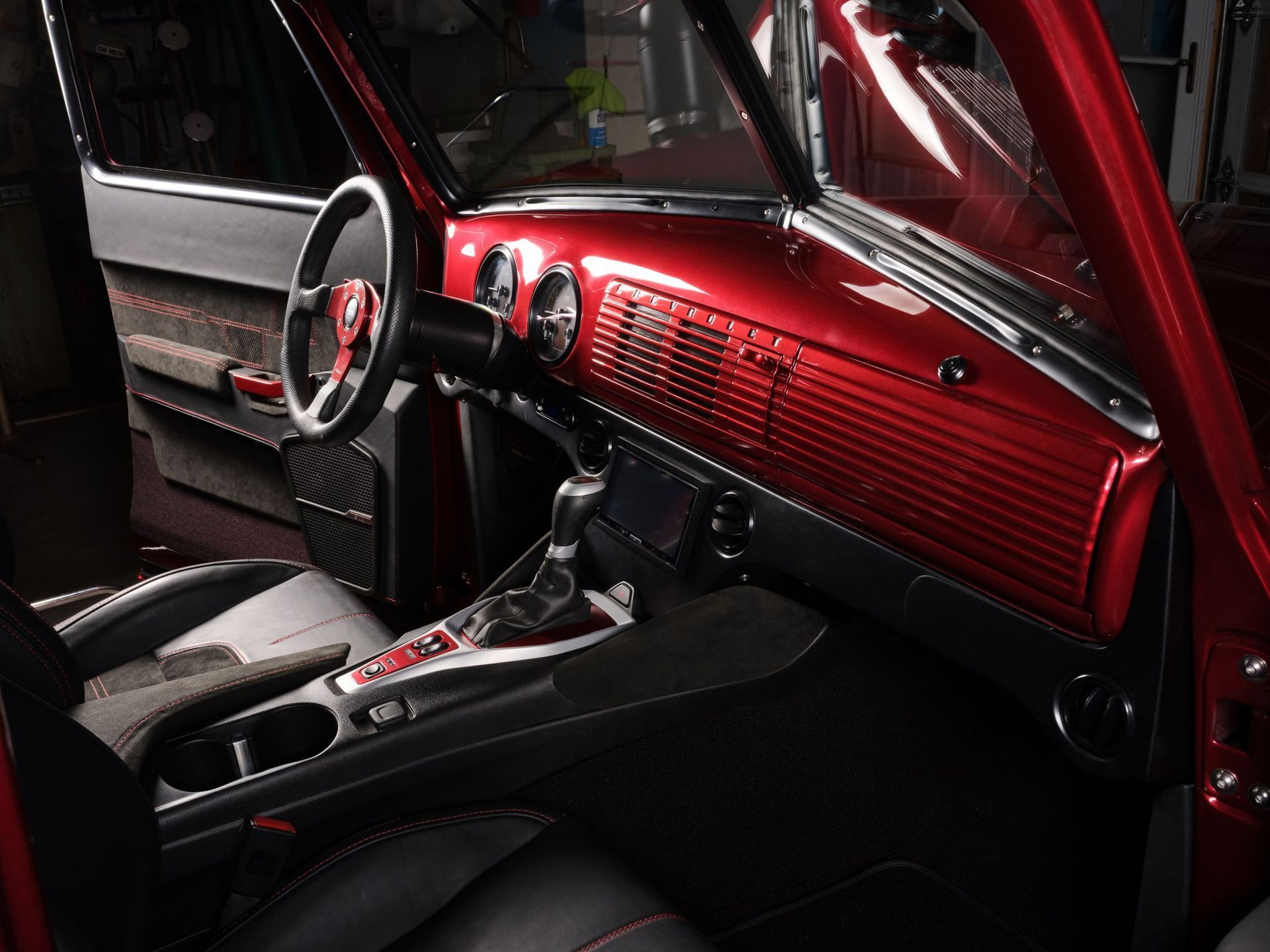 Red vintage car interior with chrome steering wheel and glossy dashboard lit by sunlight