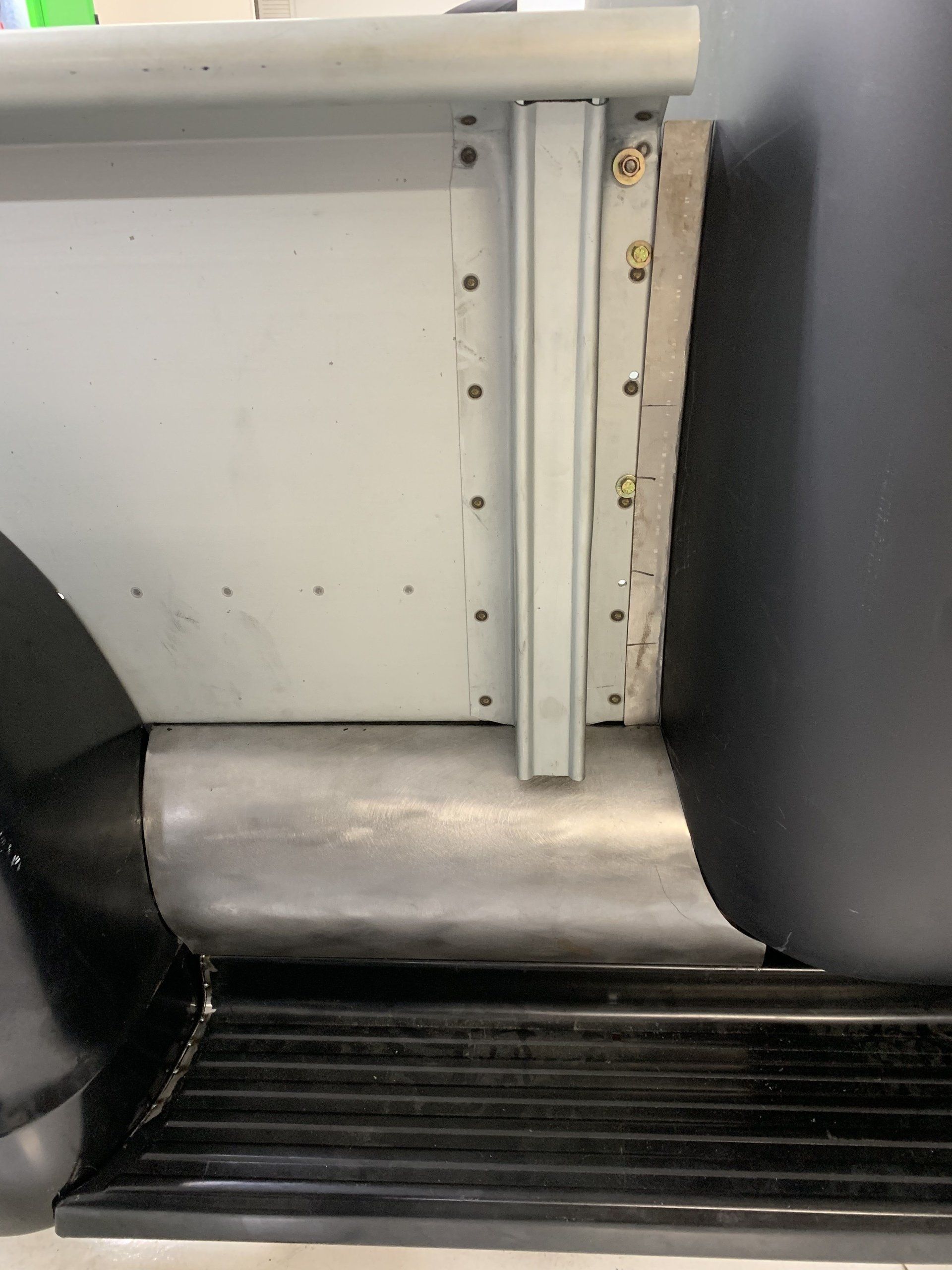 Close-up of a bus wheelchair ramp retracted by the entry step.