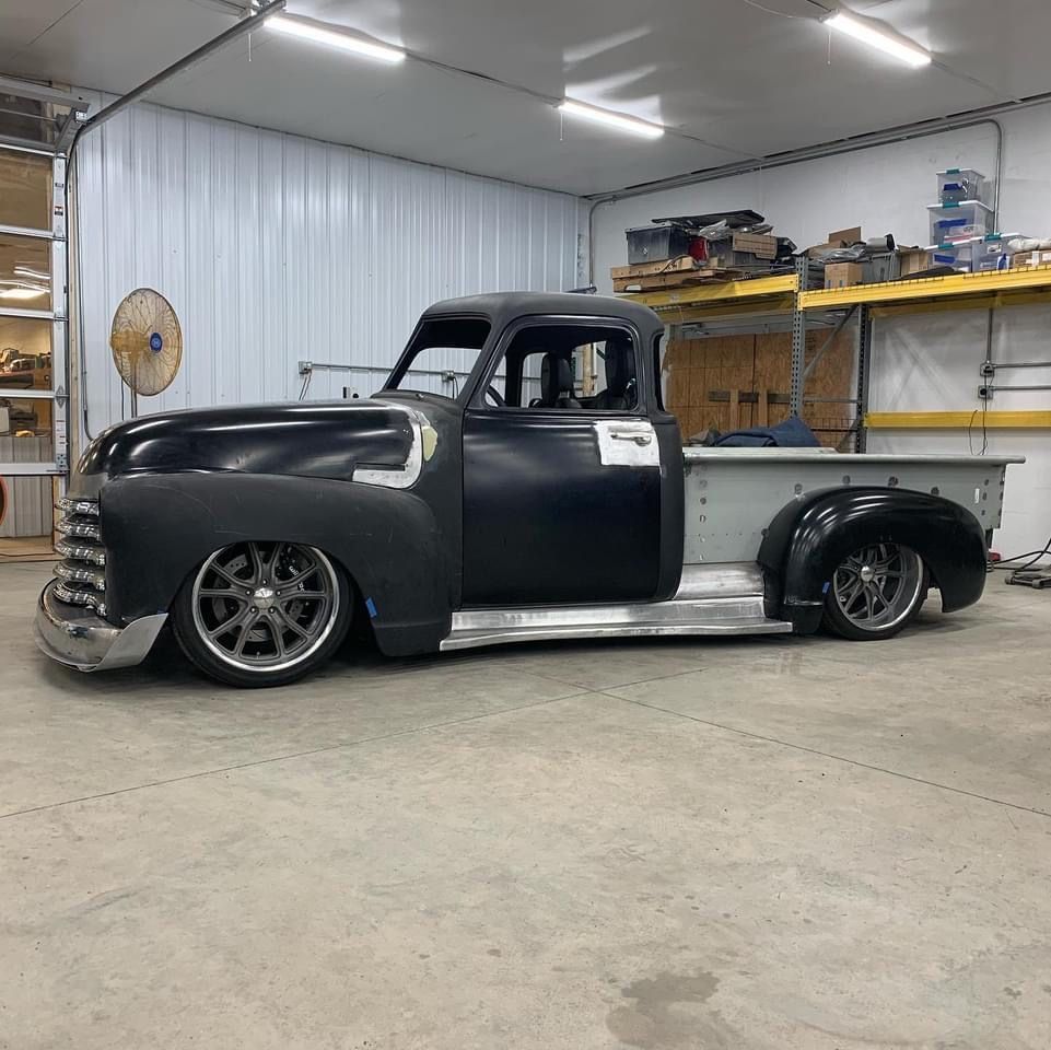 Black custom lowered vintage pickup truck in a workshop garage, side view